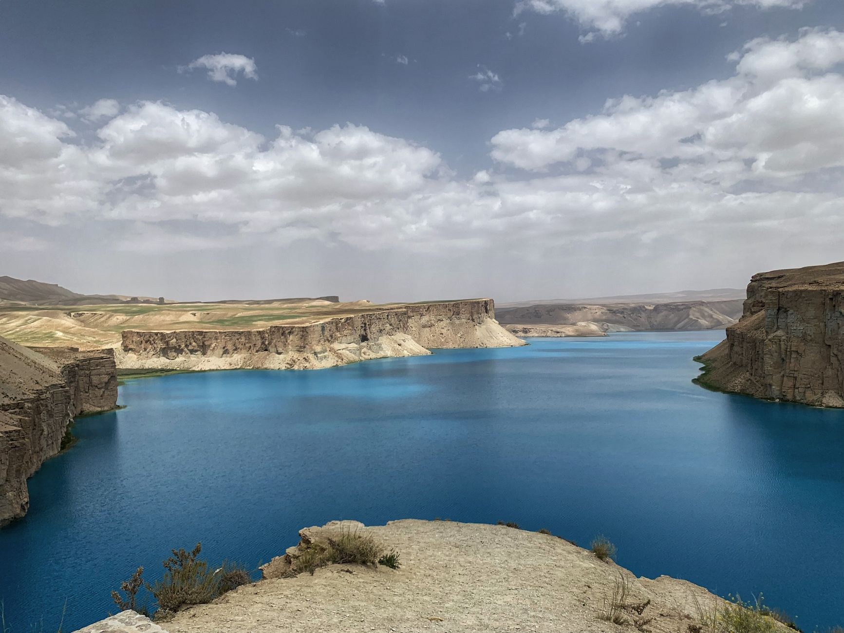 Deep azure water of a high-altitude mineral lake in Band-e Amir beneath vertical barren cliffs in Bamyan