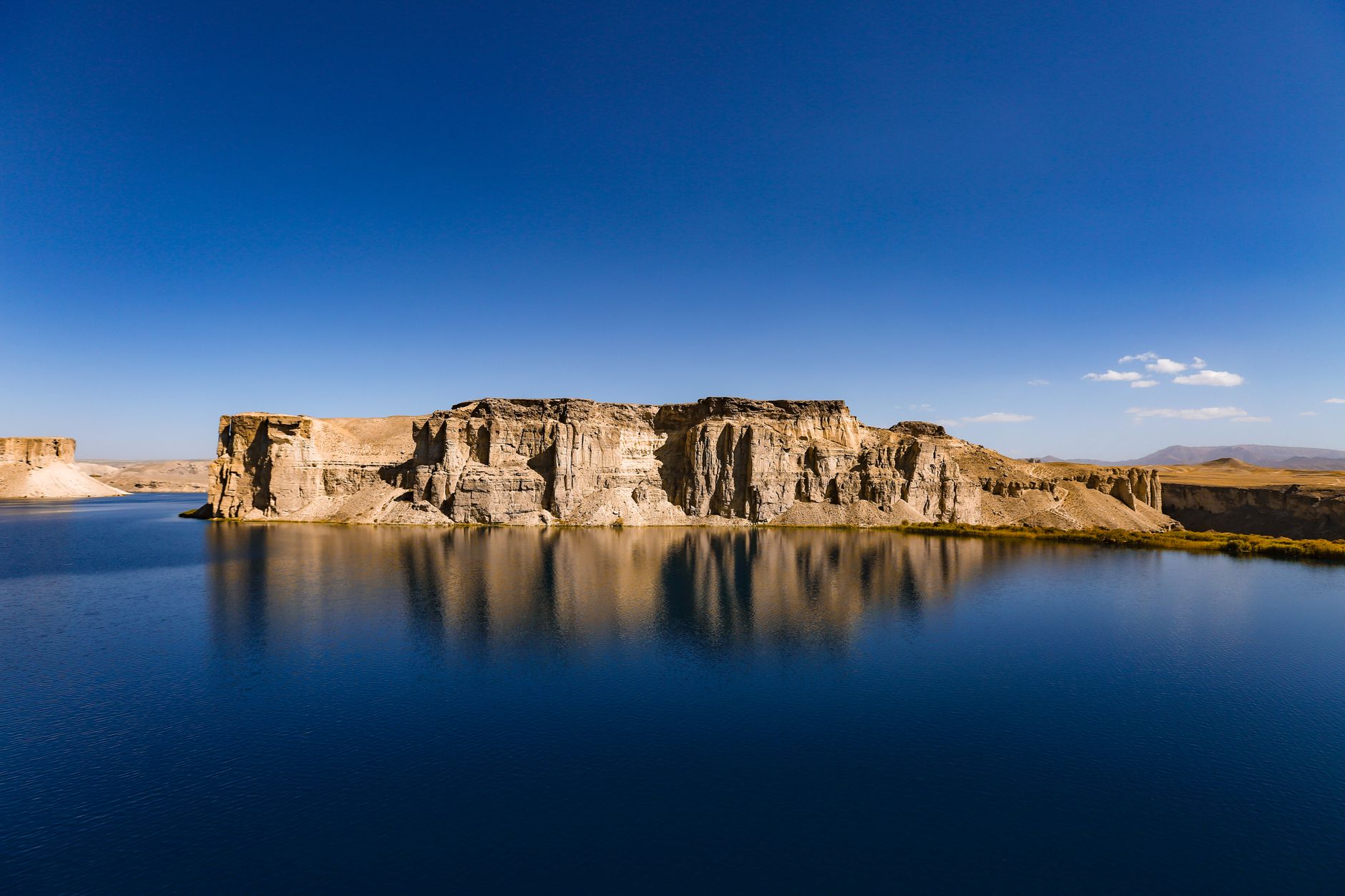 Panoramic view of Band-e Amir national park showing deep blue mineral lakes enclosed by dramatic limestone travertine cliffs in Bamyan