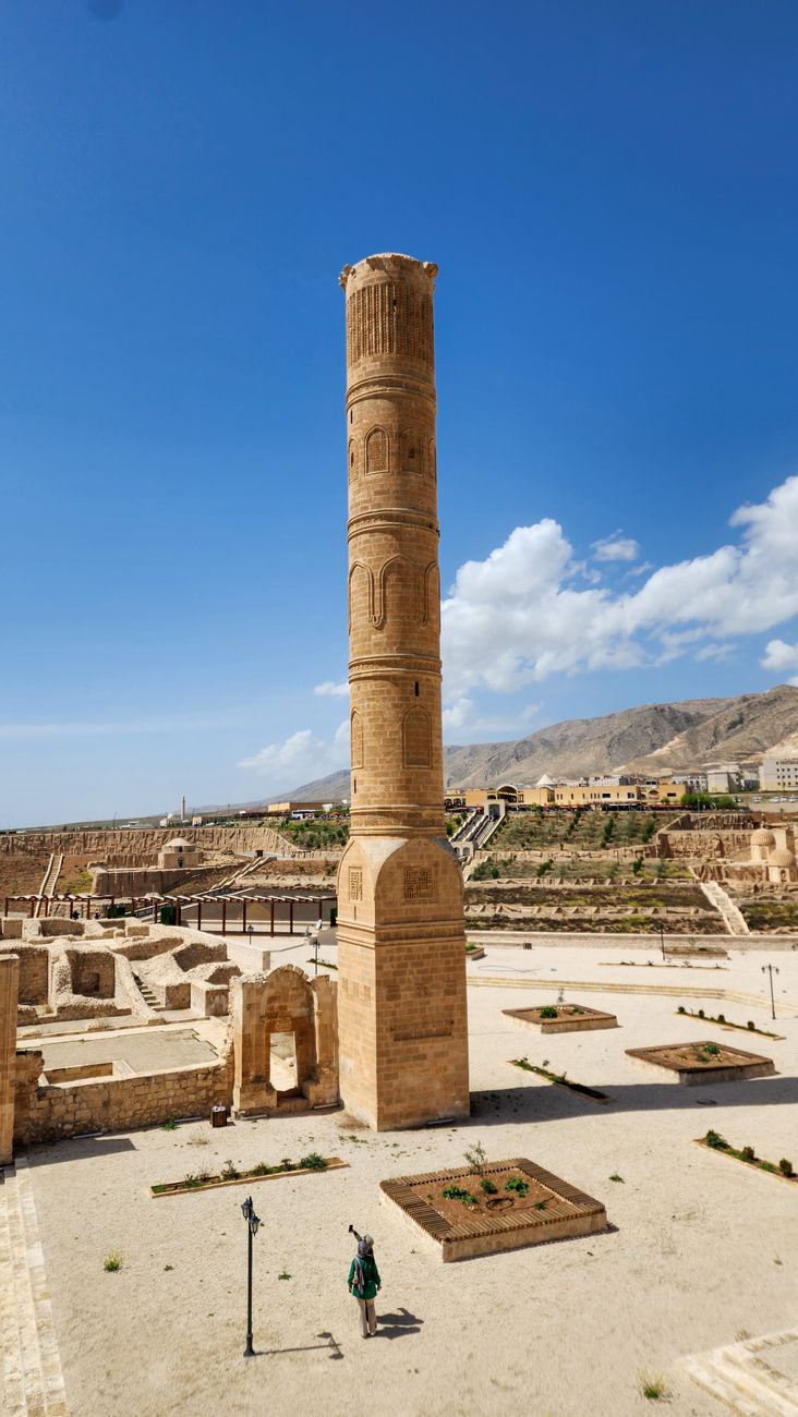 Tall historic brick minaret standing amidst archaeological ruins under a clear sky in Herat, Afghanistan