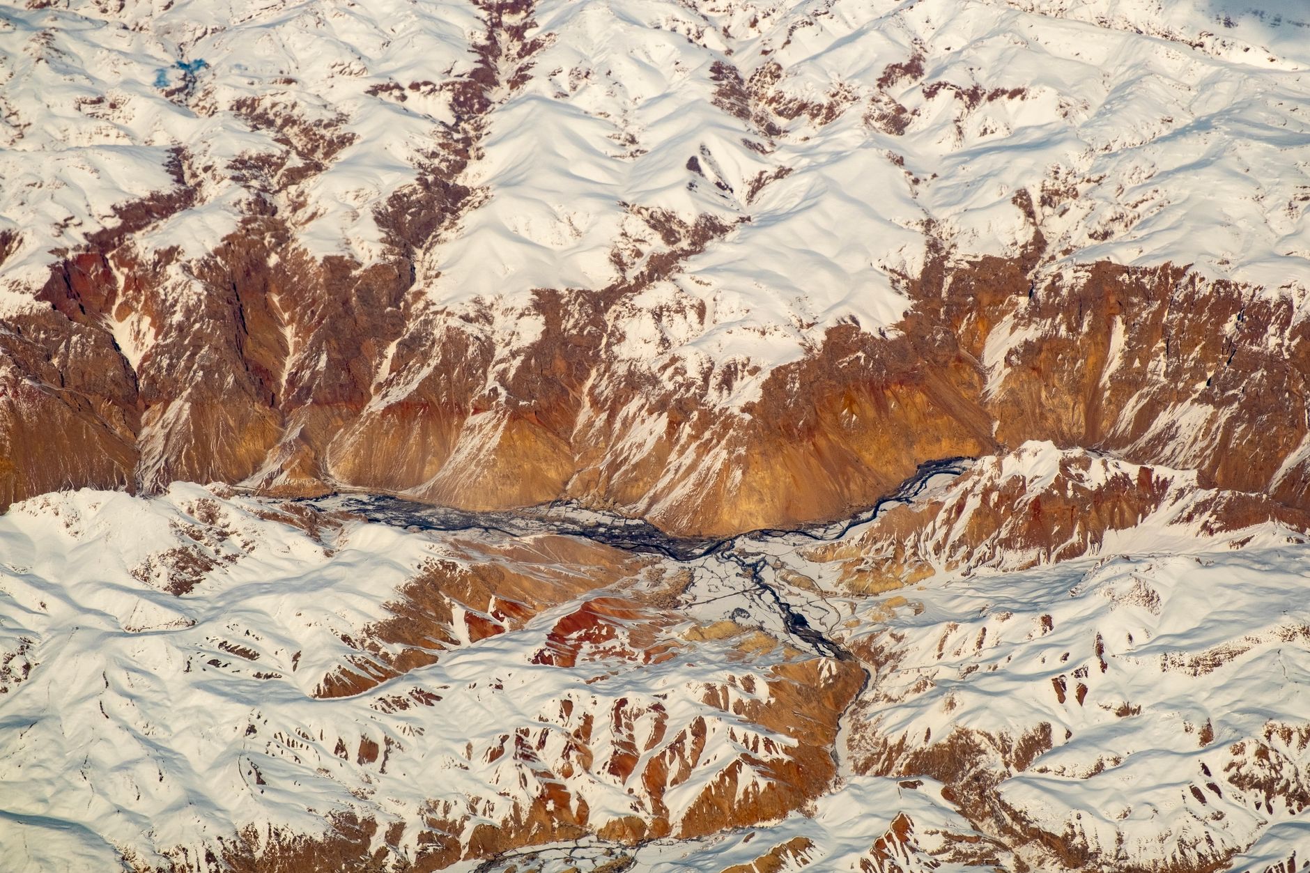 Dramatic snow-covered mountain peaks of the Hindu Kush range towering over arid valleys in northern Afghanistan