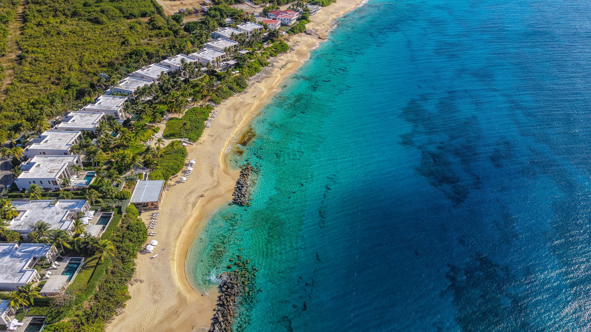 Aerial view of rugged limestone cliffs and white sand beaches along Anguilla's coral coastline