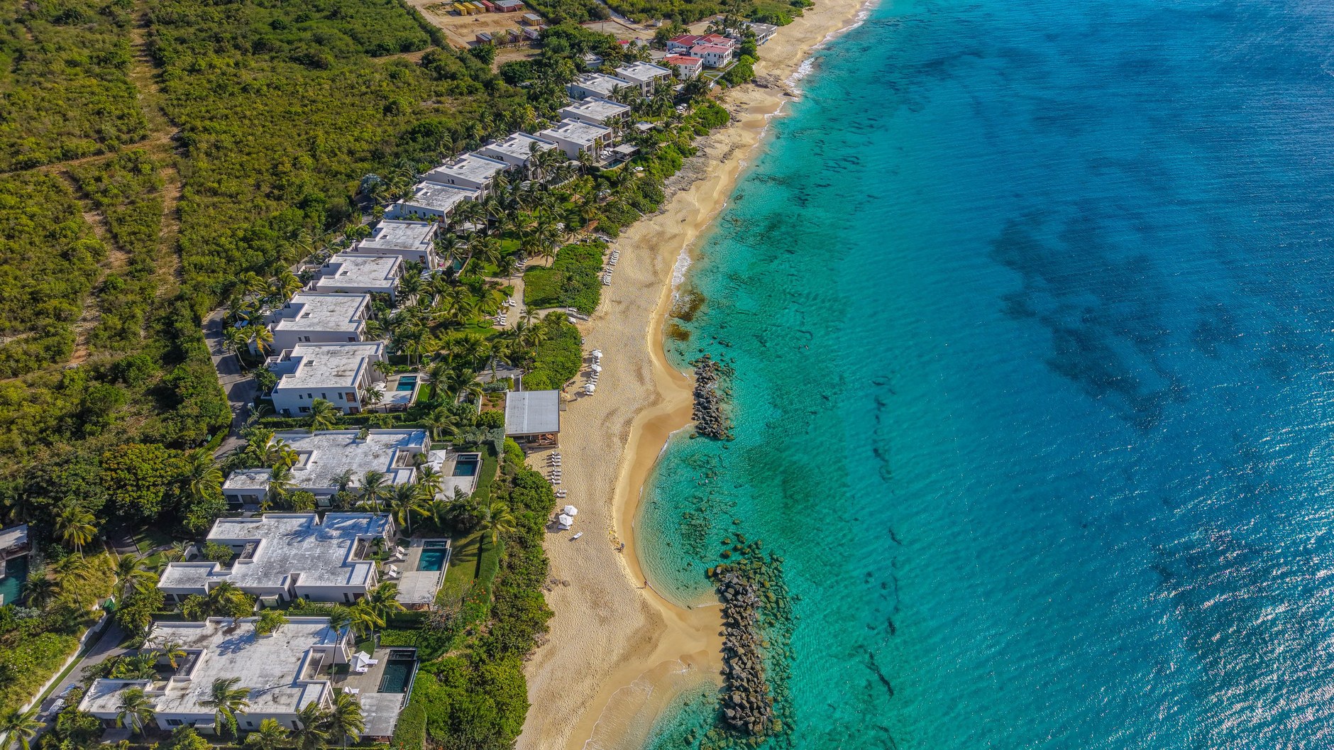 Aerial perspective across the wide white sand crescent and luxury resorts lining Meads Bay in Anguilla
