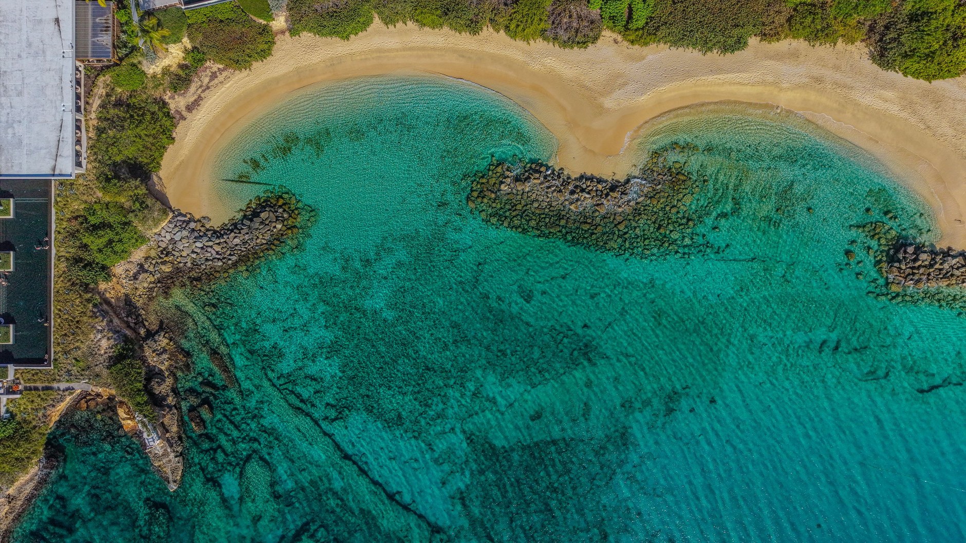Curving sandy bay with crystal-clear turquoise waters and coral formations in northern Anguilla