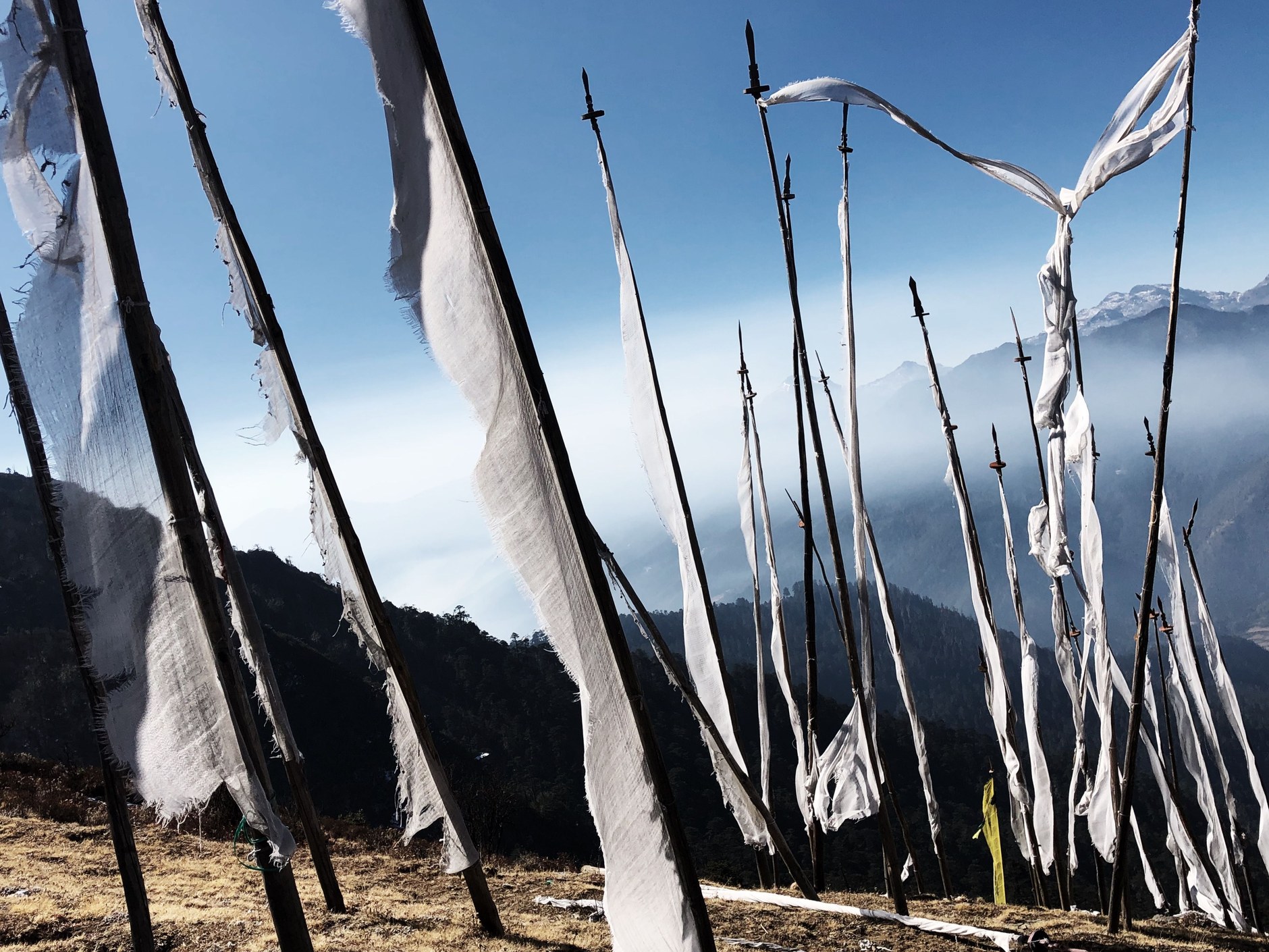 Colorful Buddhist prayer flags fluttering along a high-altitude mountain ridgeline against Himalayan peaks