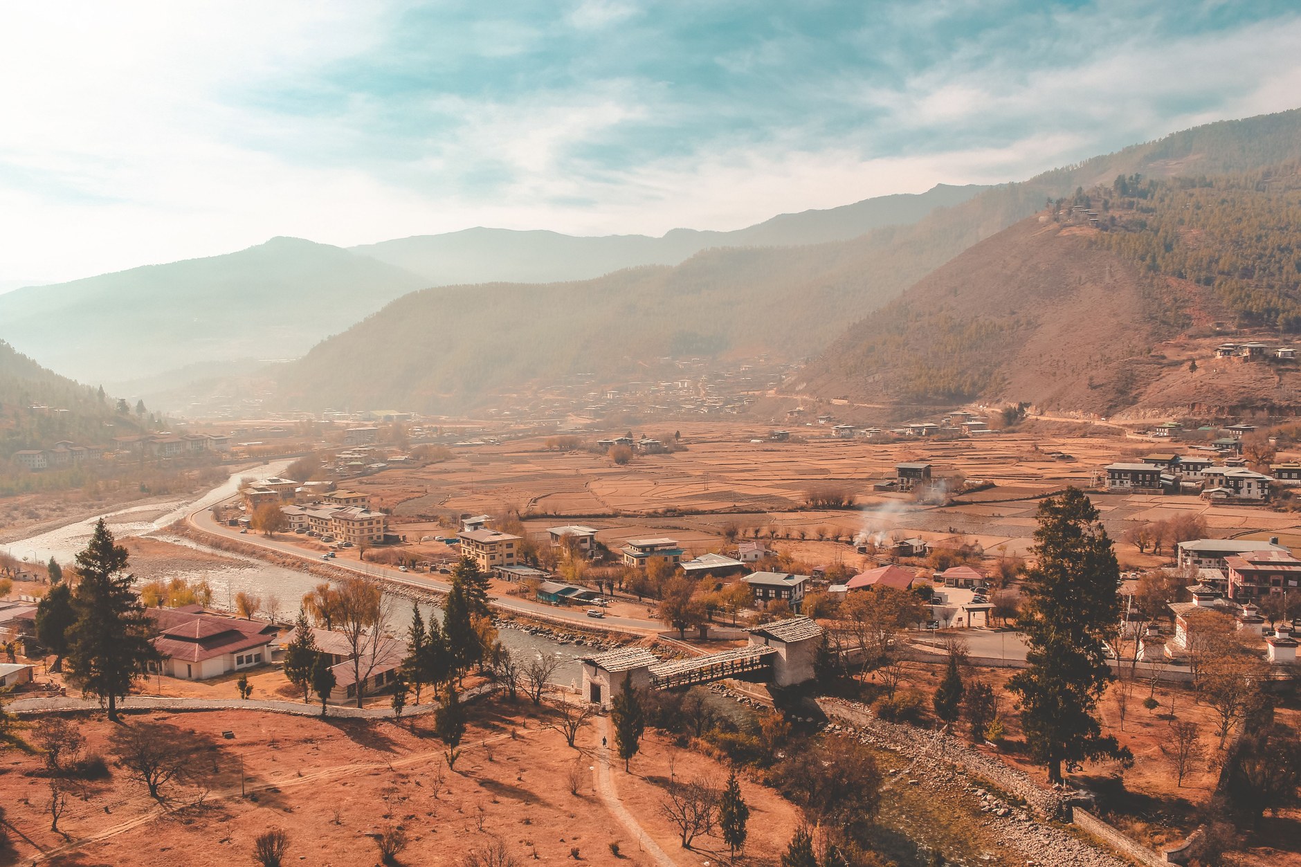 Traditional multi-story whitewashed Bhutanese farmhouses set among terraced green fields in Paro Valley