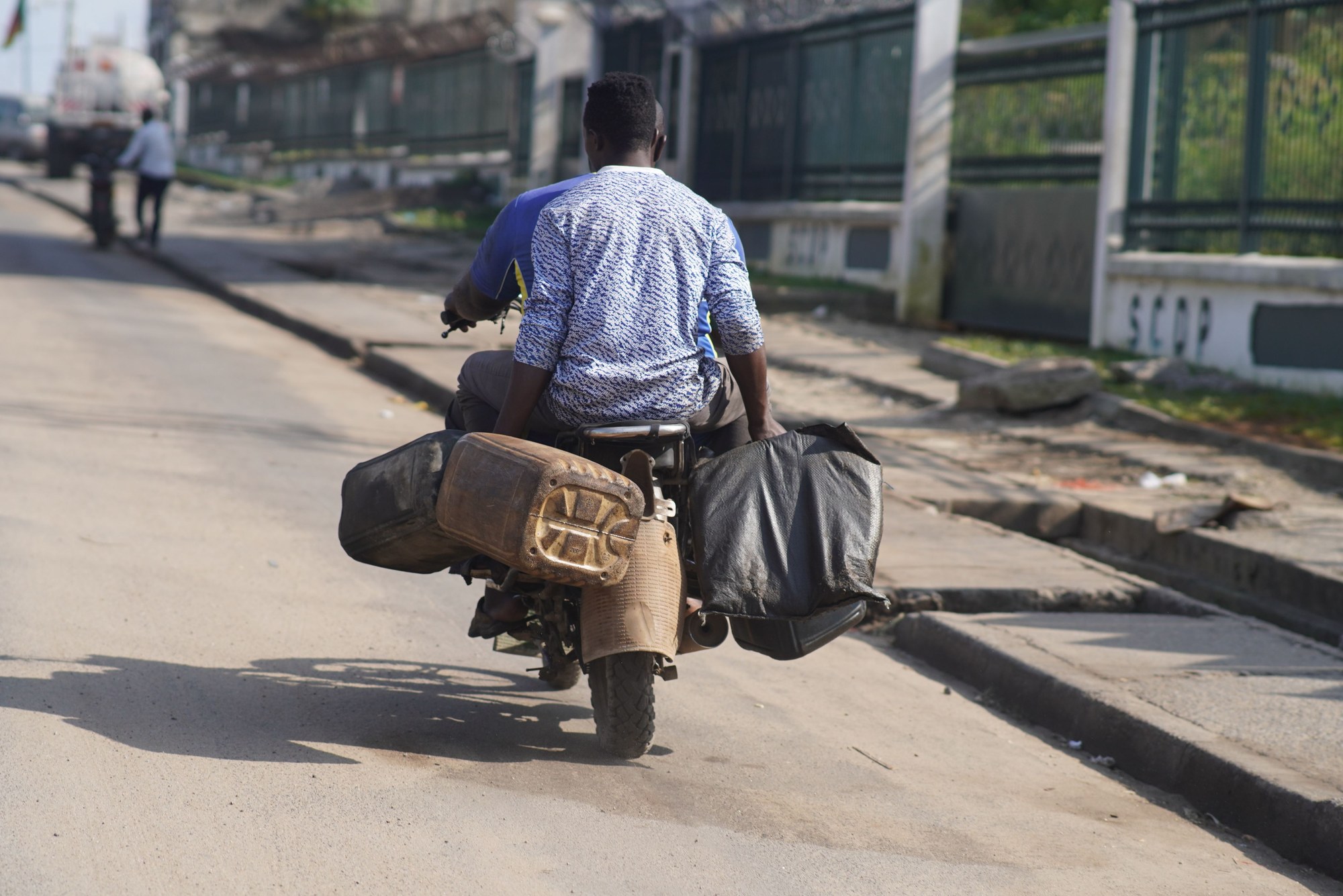 Street scene in Douala showing a motorcycle loaded with cargo moving through an urban commercial district