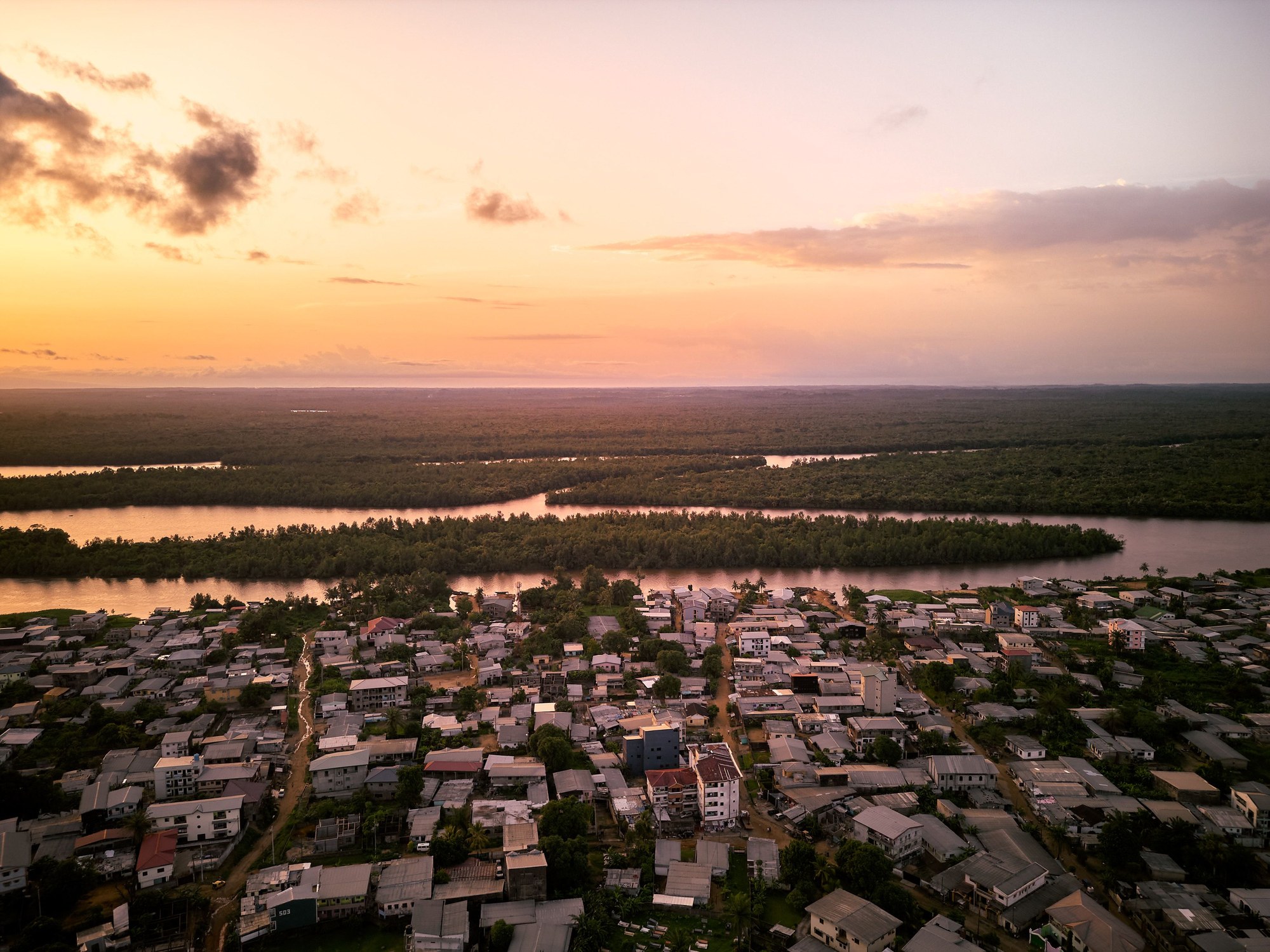 Sunset over the wide Wouri River estuary in Douala with boat traffic and industrial port docks in the distance