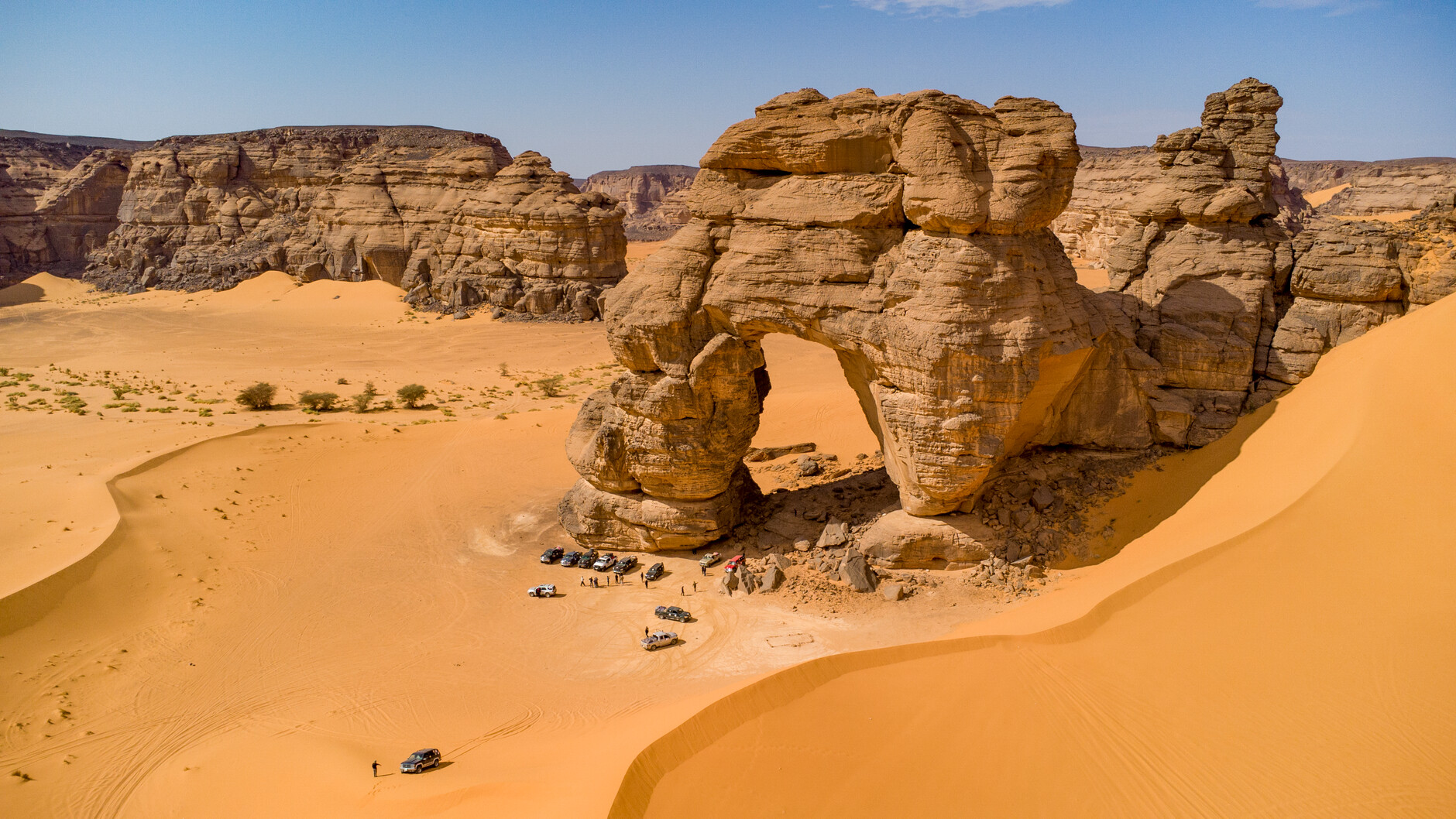Aerial perspective of a colossal natural sandstone arch standing in the desert plains of northeastern Chad