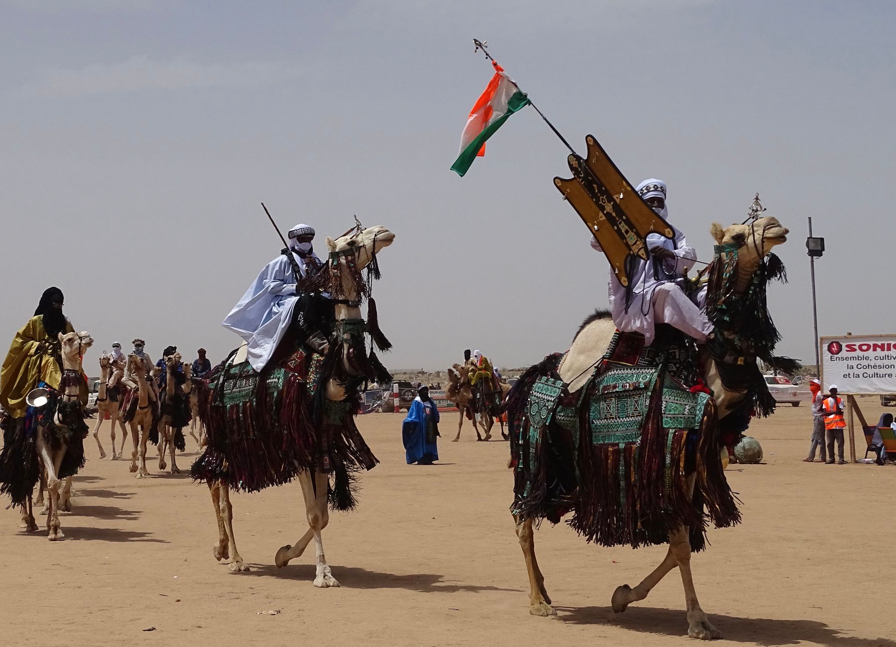 Group of nomadic Sahelian herders guiding dromedary camels across arid scrubland in central Chad