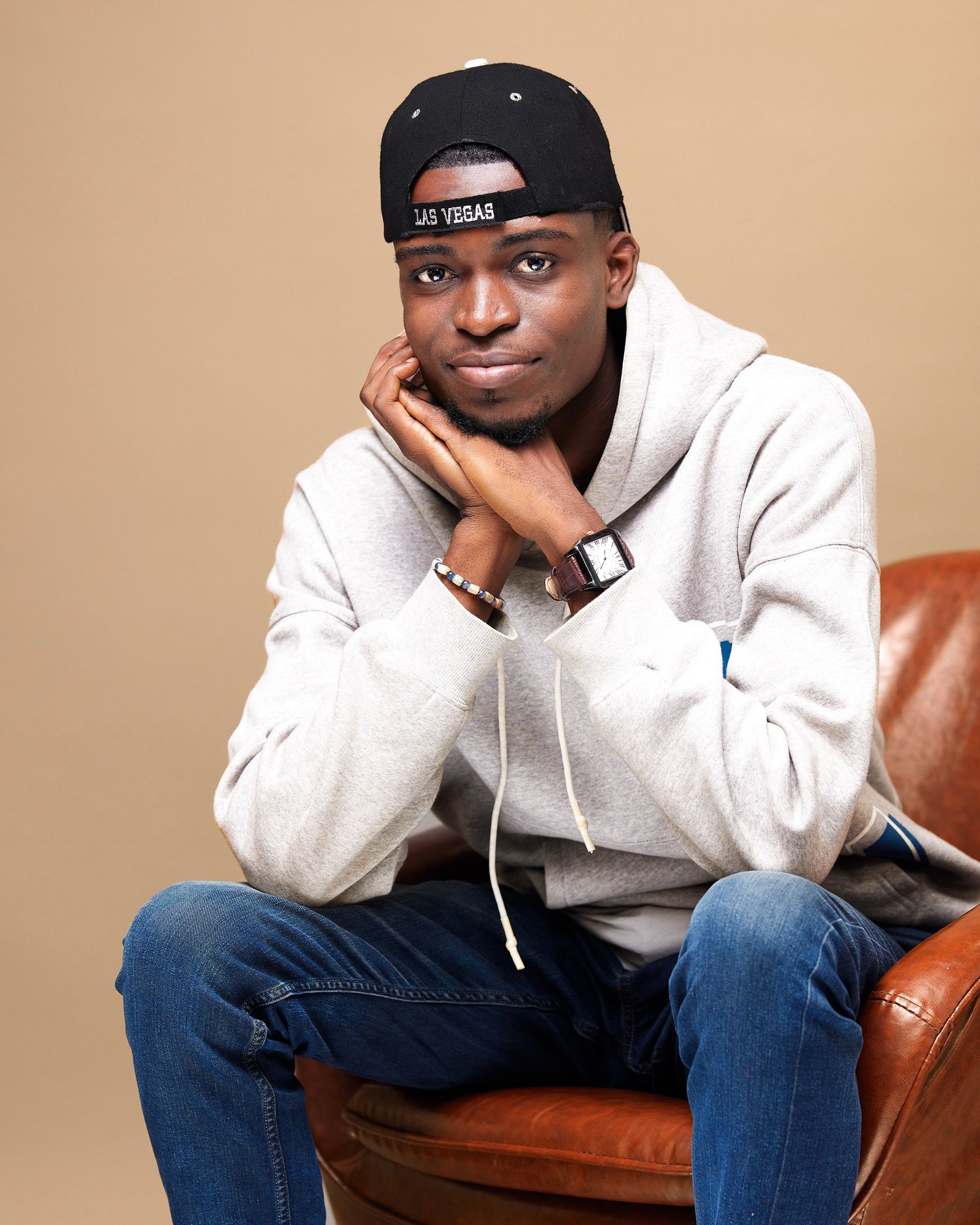 Young man in relaxed casual attire seated outdoors in Kinshasa reflecting urban youth culture