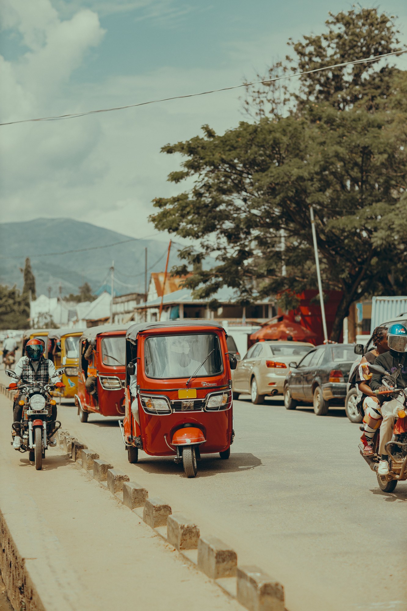 Busy urban street in South Kivu with colorful motorized three-wheelers and motorcycles in daily traffic
