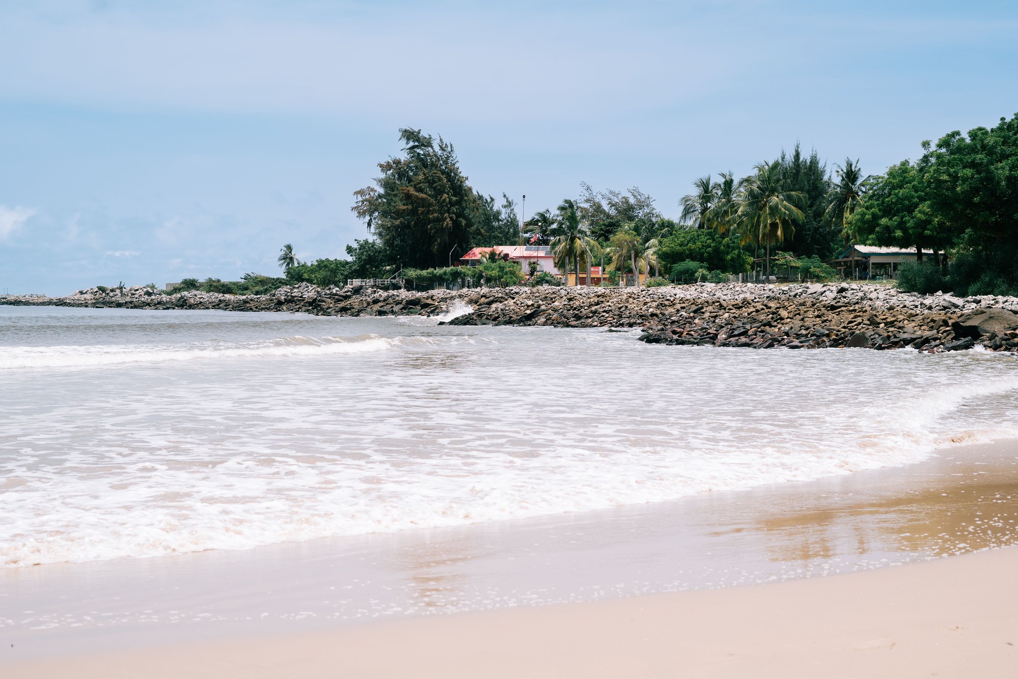 Atlantic coastline in Pointe-Noire with palm trees and ocean surf rolling onto the sand