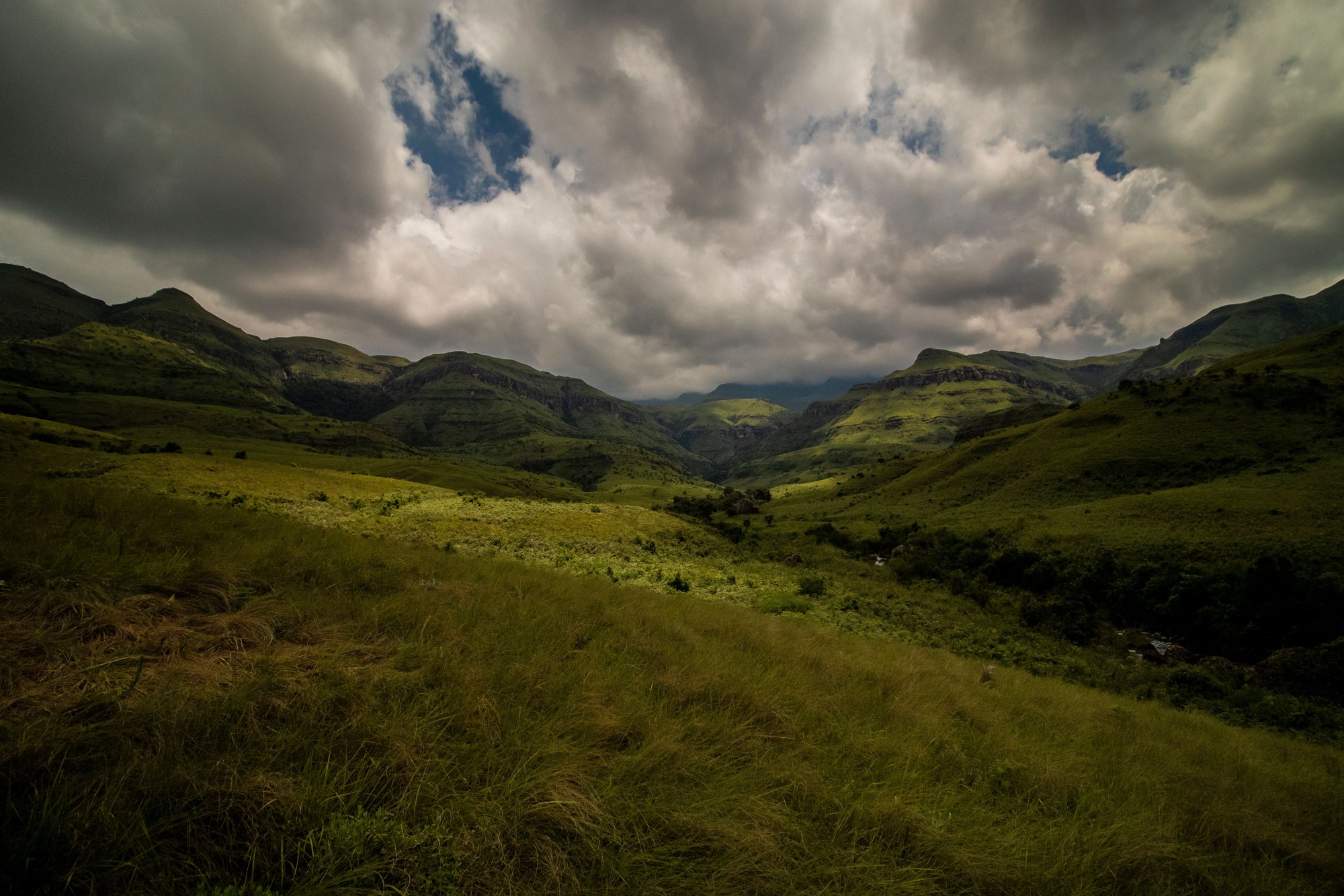 Expansive green mountain ridges and dramatic escarpments under clear skies