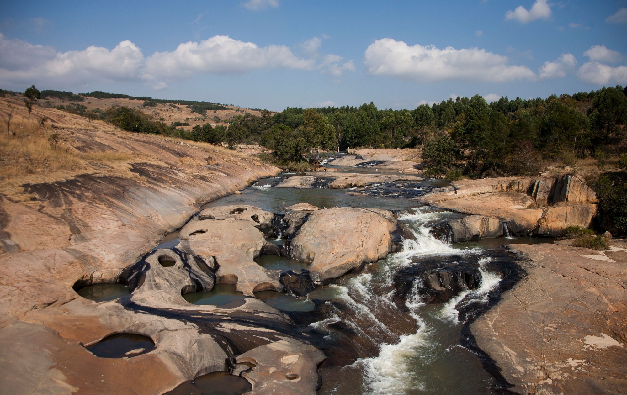 Rocky river cascades and lush trees along a scenic river in Eswatini
