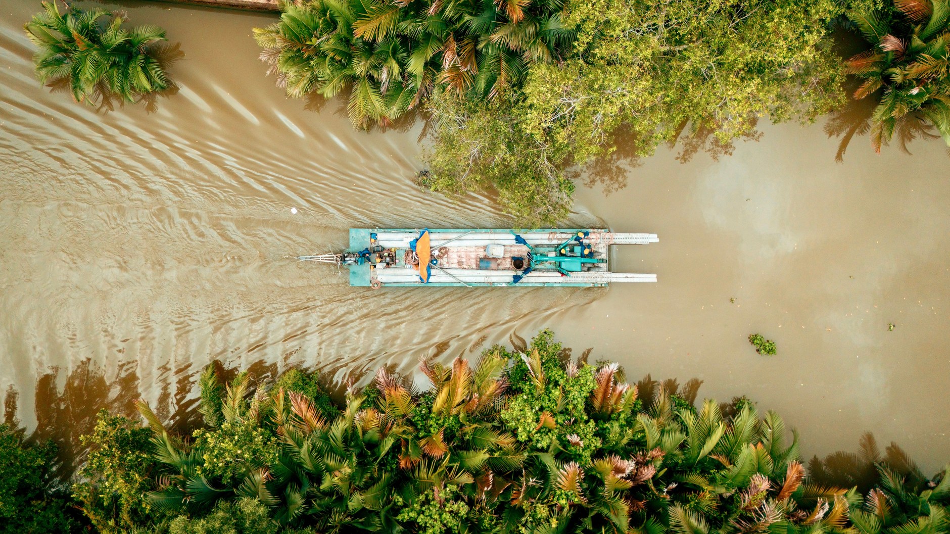 Motorized river boat navigating lush mangrove waterways toward remote rainforest lodges