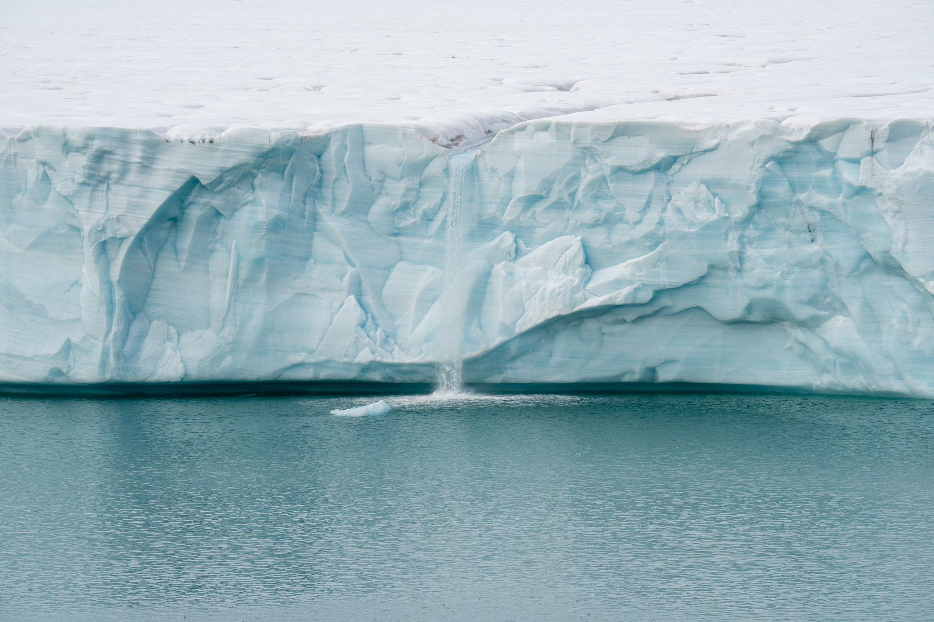 The towering ice face of Eqi Glacier calving into the fjord