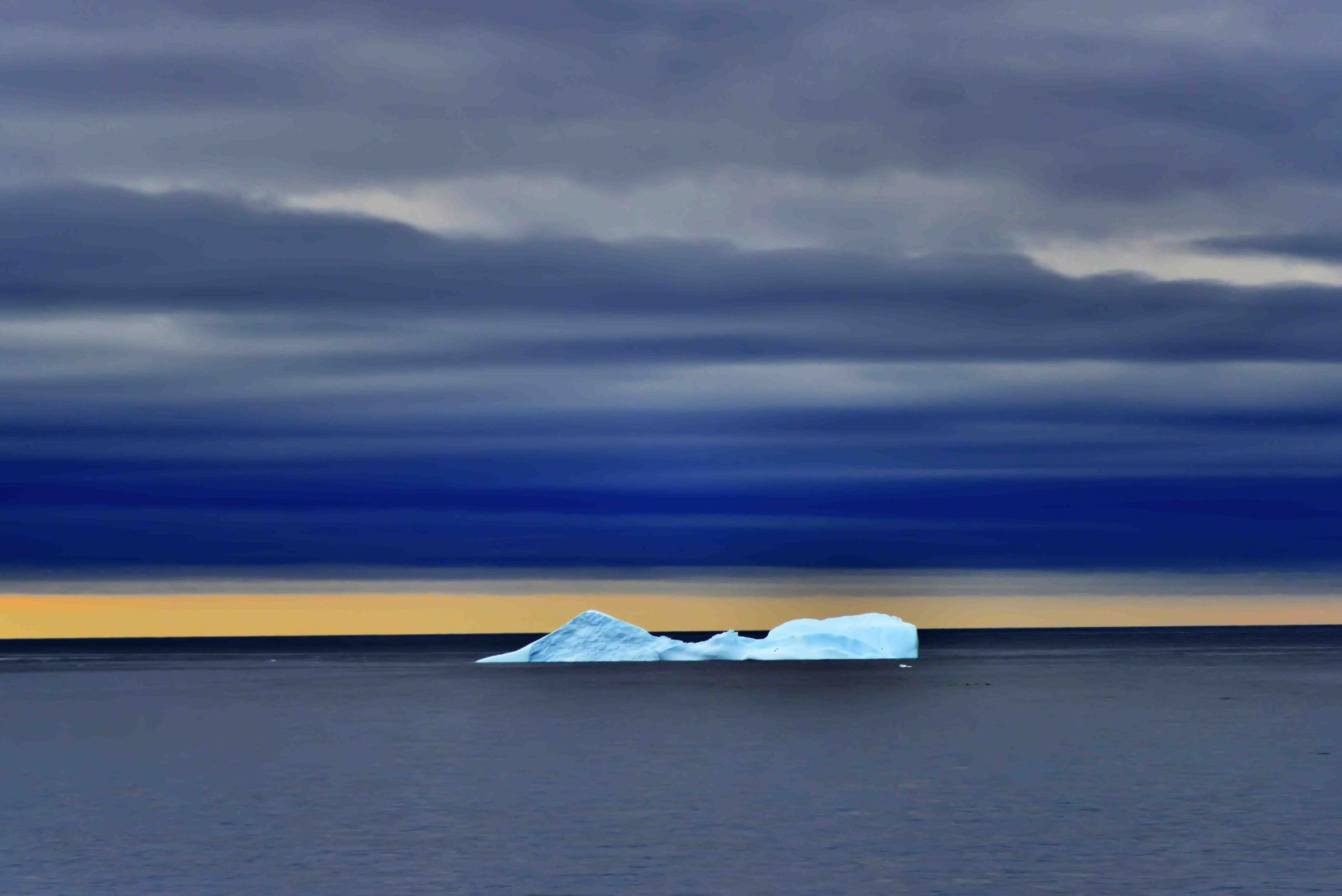 Golden midnight sun illuminating floating icebergs in Disko Bay