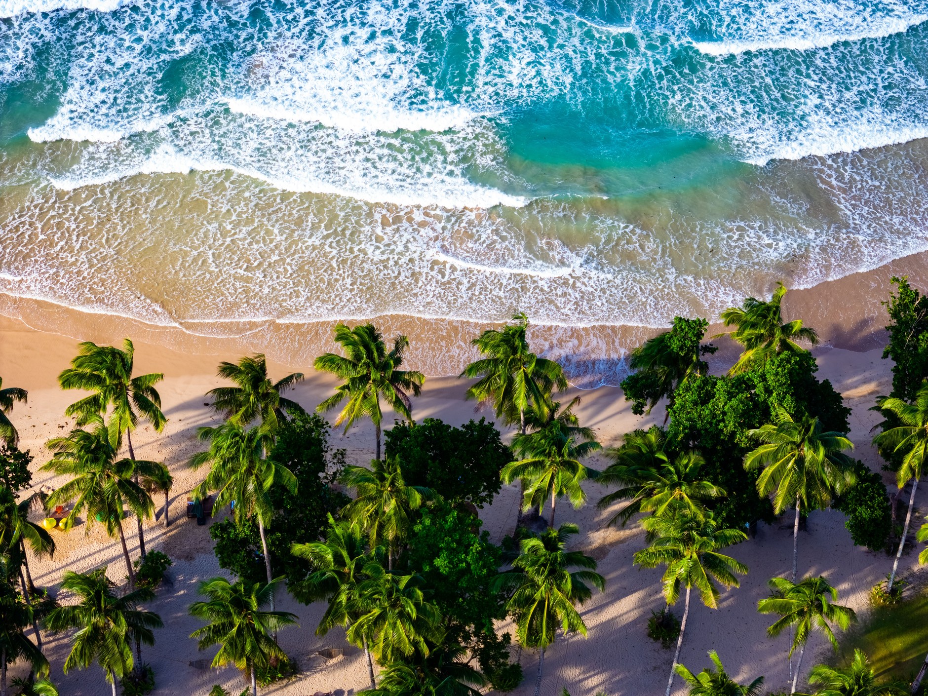 Turquoise waters and white coral sand along the curved shoreline of Tumon Bay