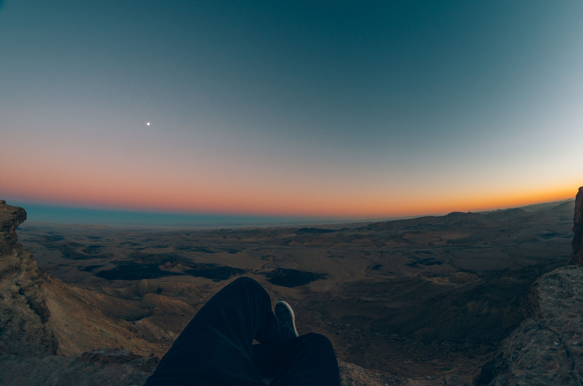 Dramatic sunset over vast desert crater and multi-colored geological rock layers