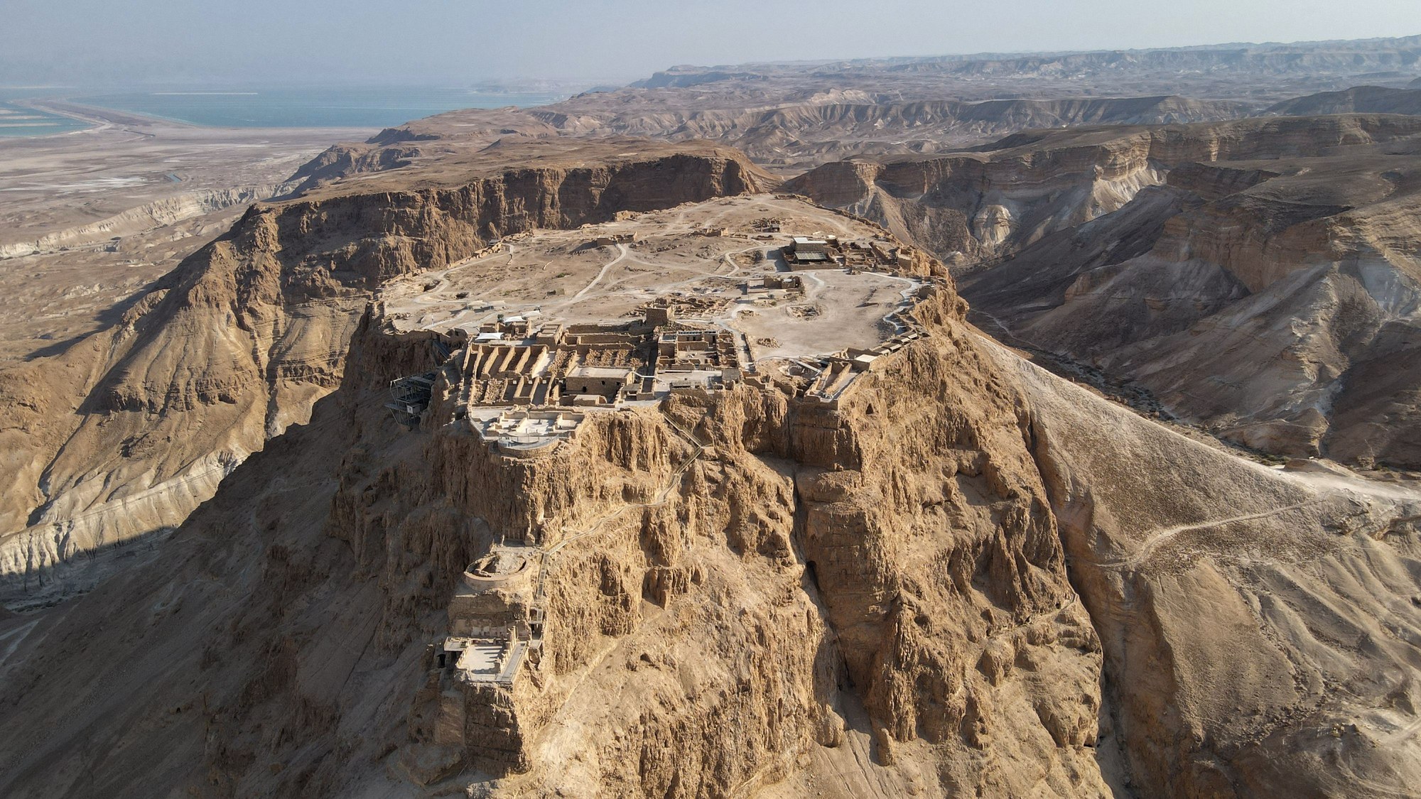 Aerial perspective of the rugged desert plateau and stone ruins of Masada fortress