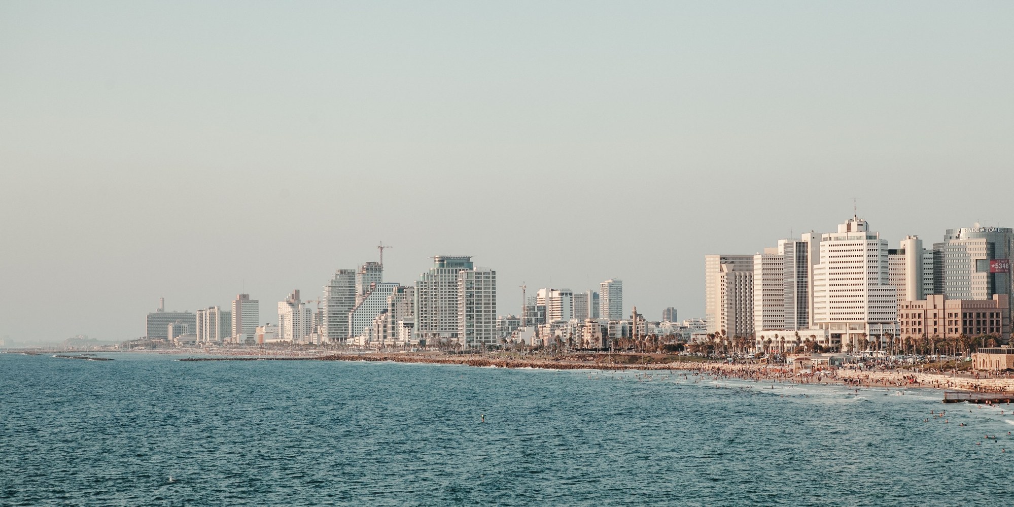 Modern city skyline and sandy beach promenade stretching along the Mediterranean sea