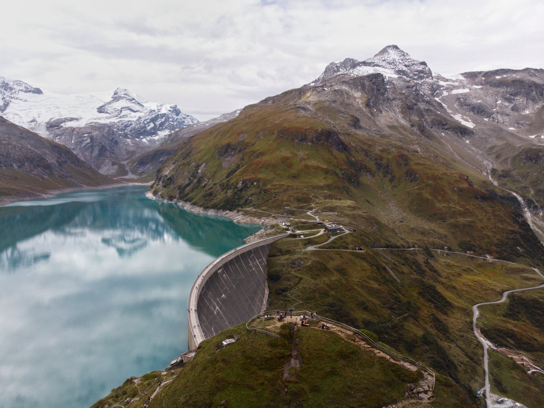 Towering concrete arch and deep blue reservoir waters of Katse Dam surrounded by mountains