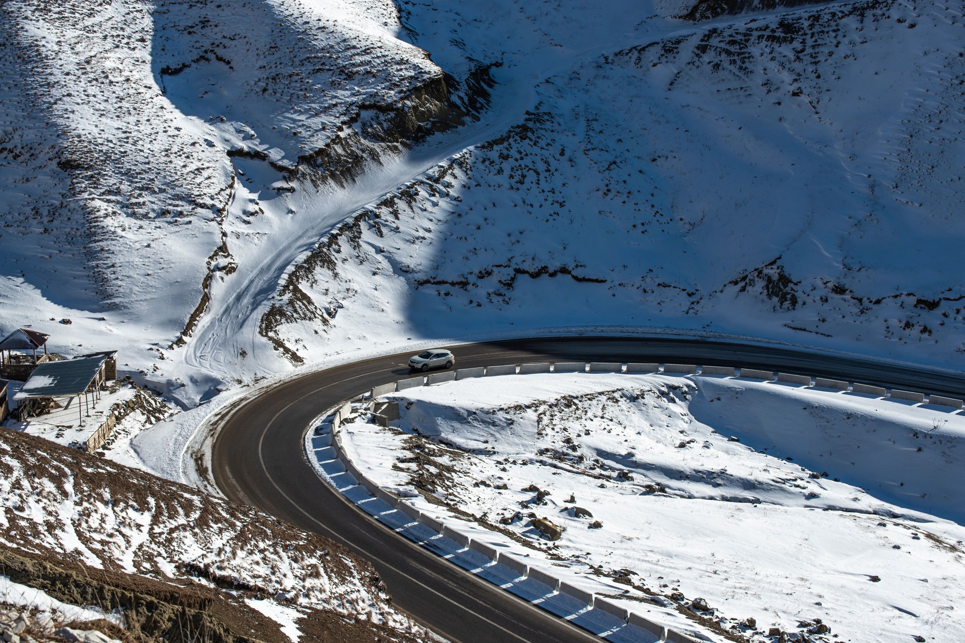 Paved alpine road carving through steep mountain ridges over 3000 meters above sea level