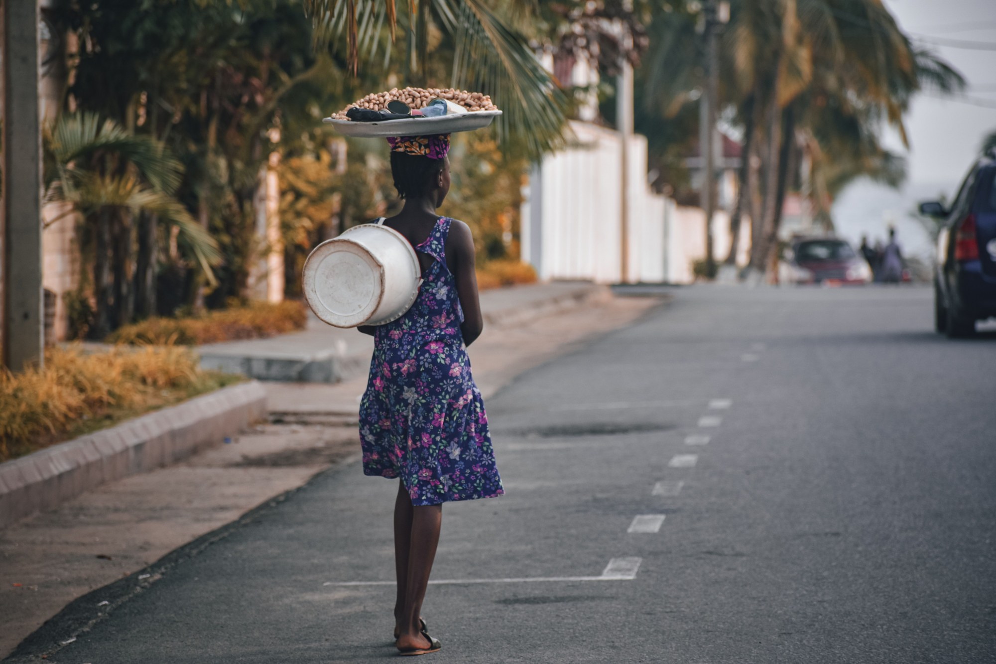 Street scene in central Monrovia with pedestrians walking past commercial shops and palm trees