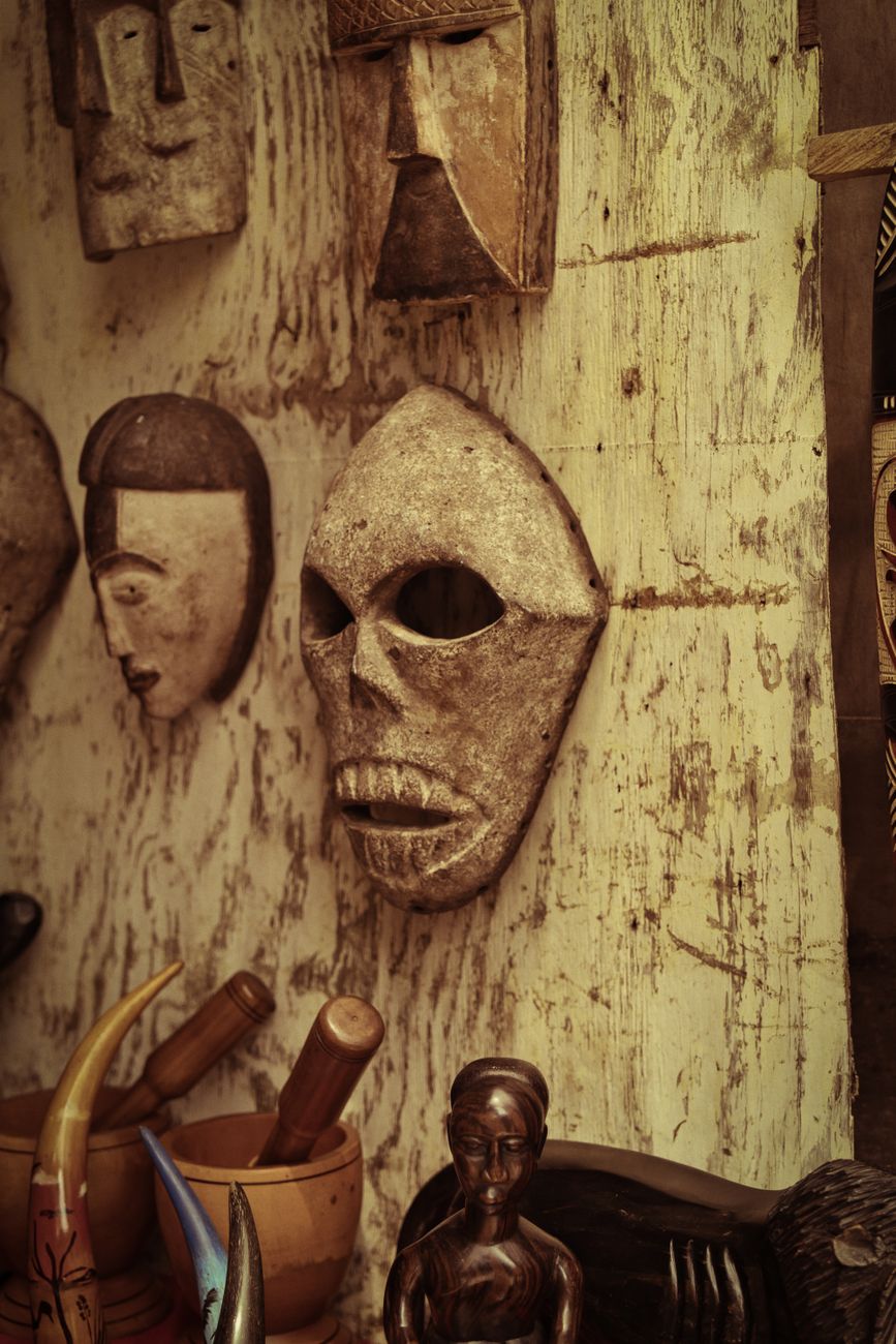 Traditional West African hand-carved ceremonial wooden masks and sculptures on display at an artisan market