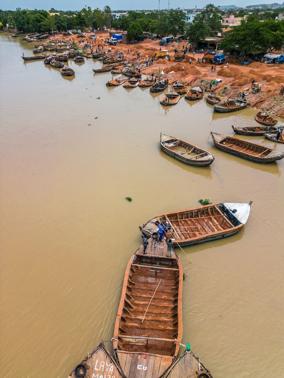 Traditional wooden pirogue boats clustered along the Niger River shoreline in Bamako, Mali
