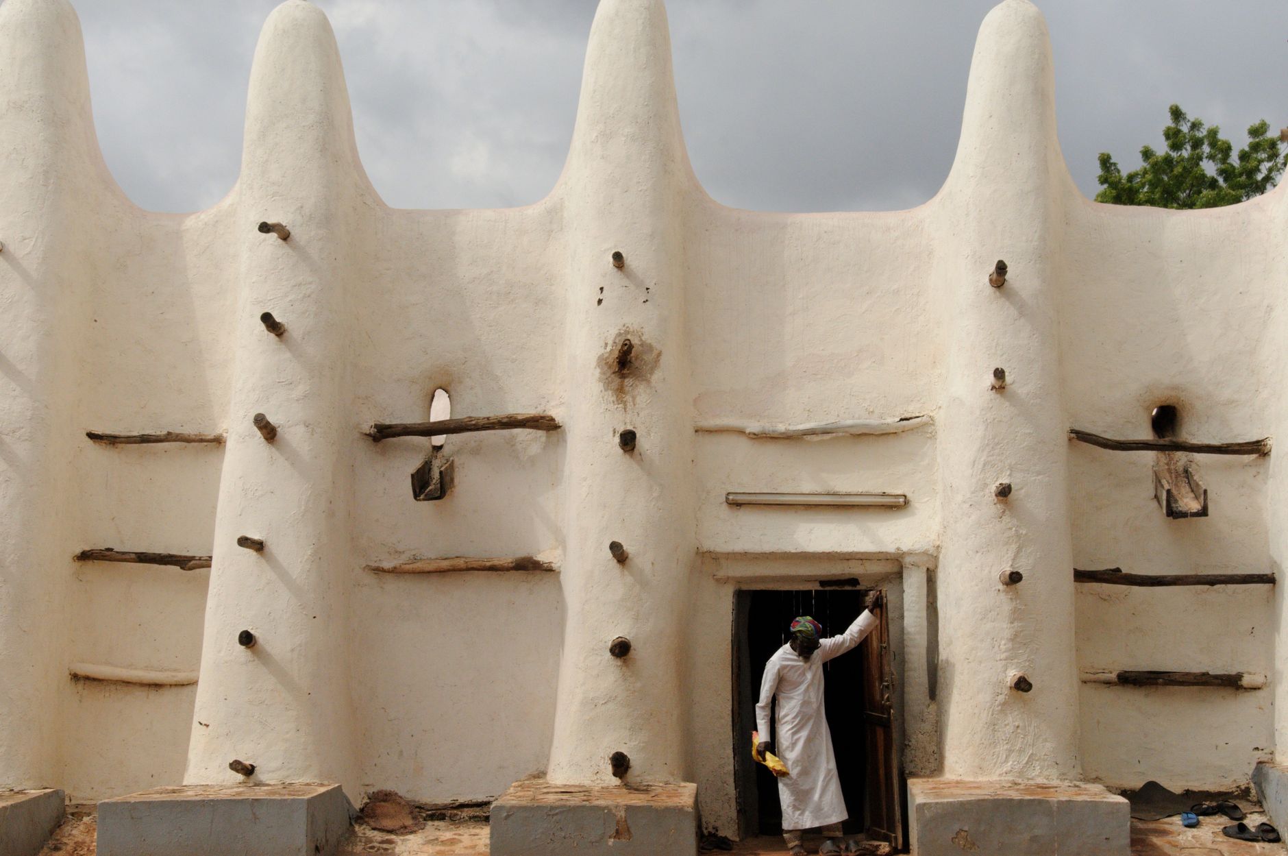 Sudano-Sahelian adobe earthen building with protruding timber toron beams under Sahelian skies