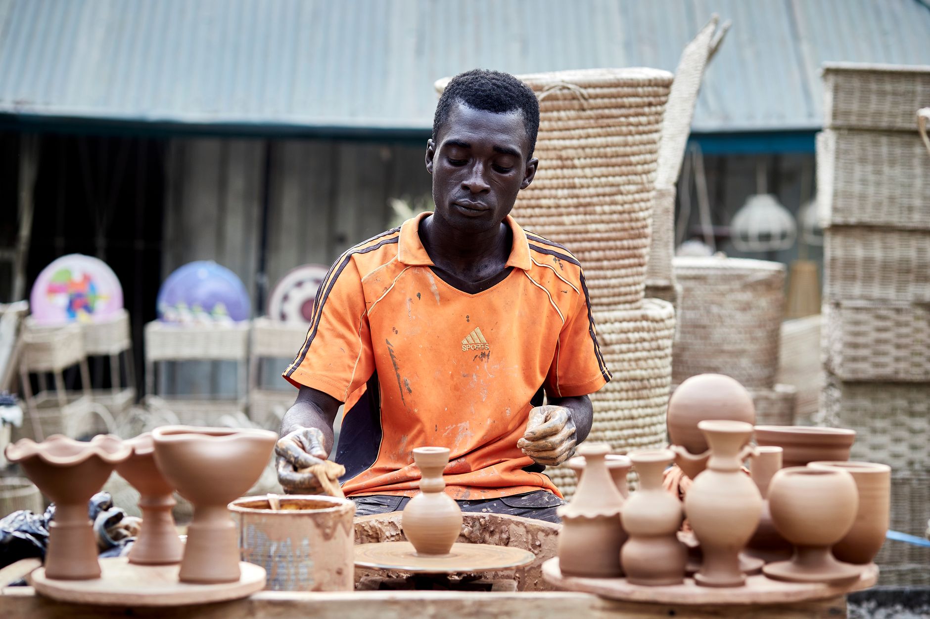 Malian artisan hand-shaping traditional terracotta clay pots in an open-air workshop