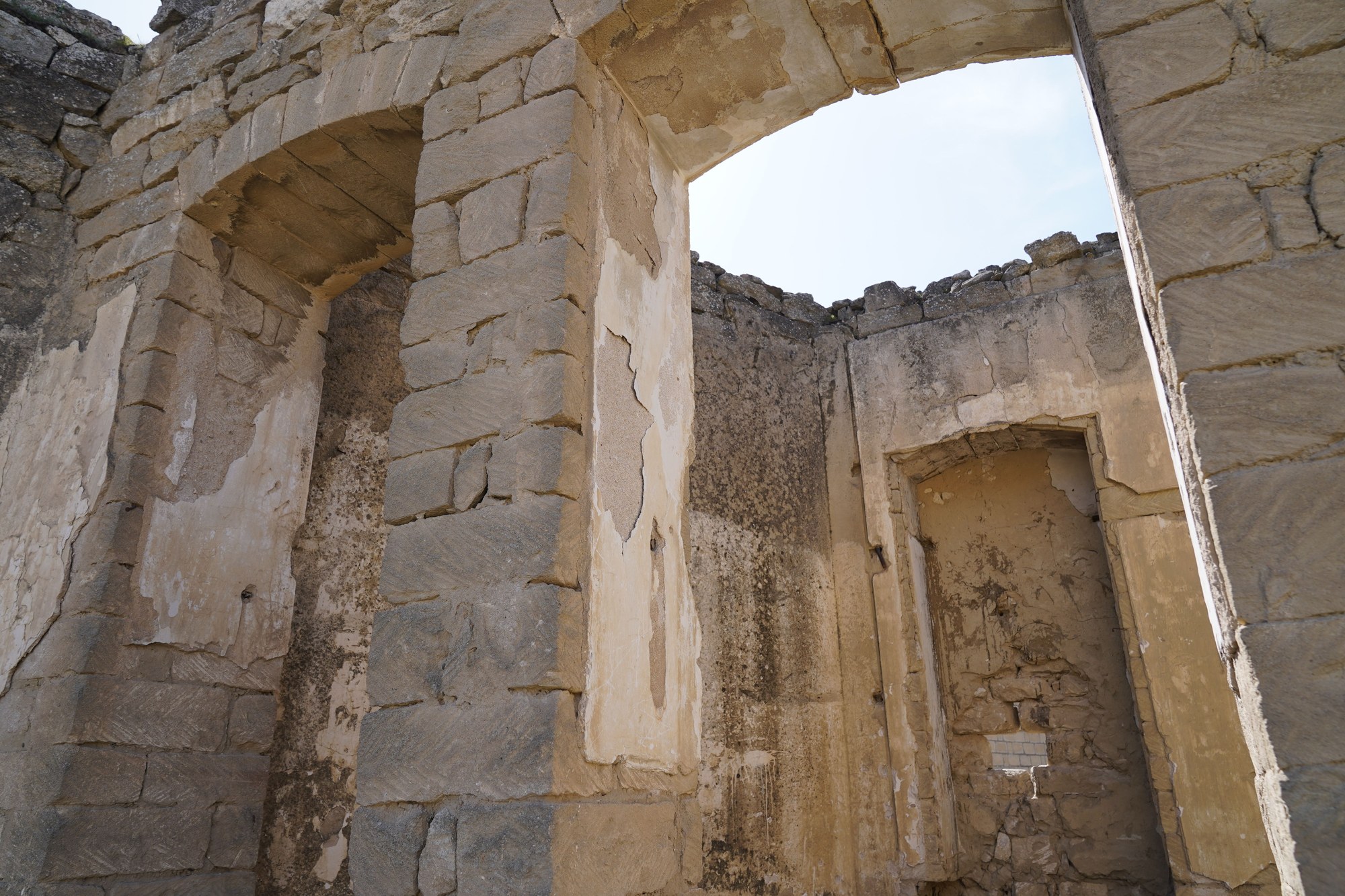 Weathered historic stone ruins and arched doorways partially buried in sediment