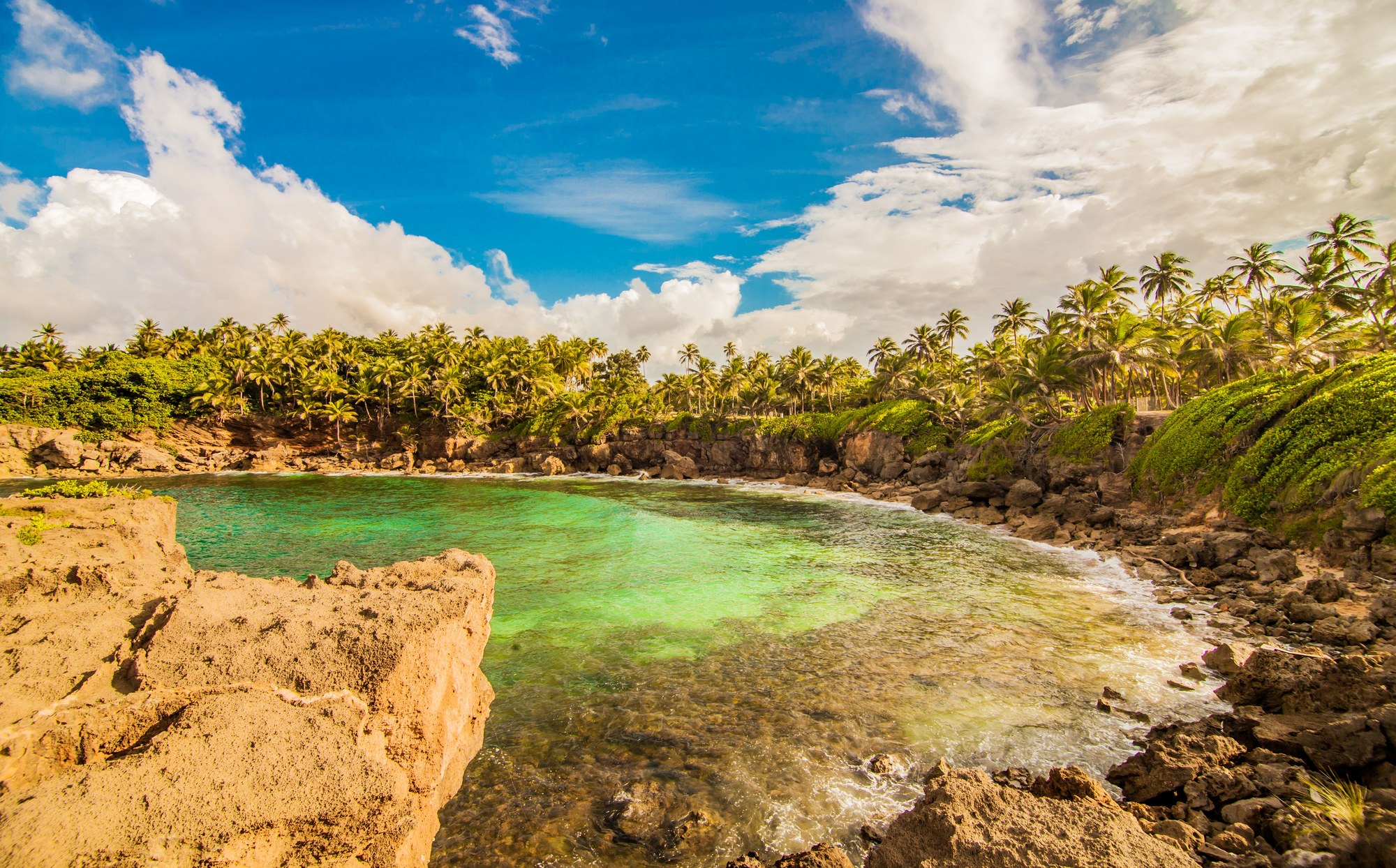 Secluded tropical cove with clear turquoise ocean water and green cliffs