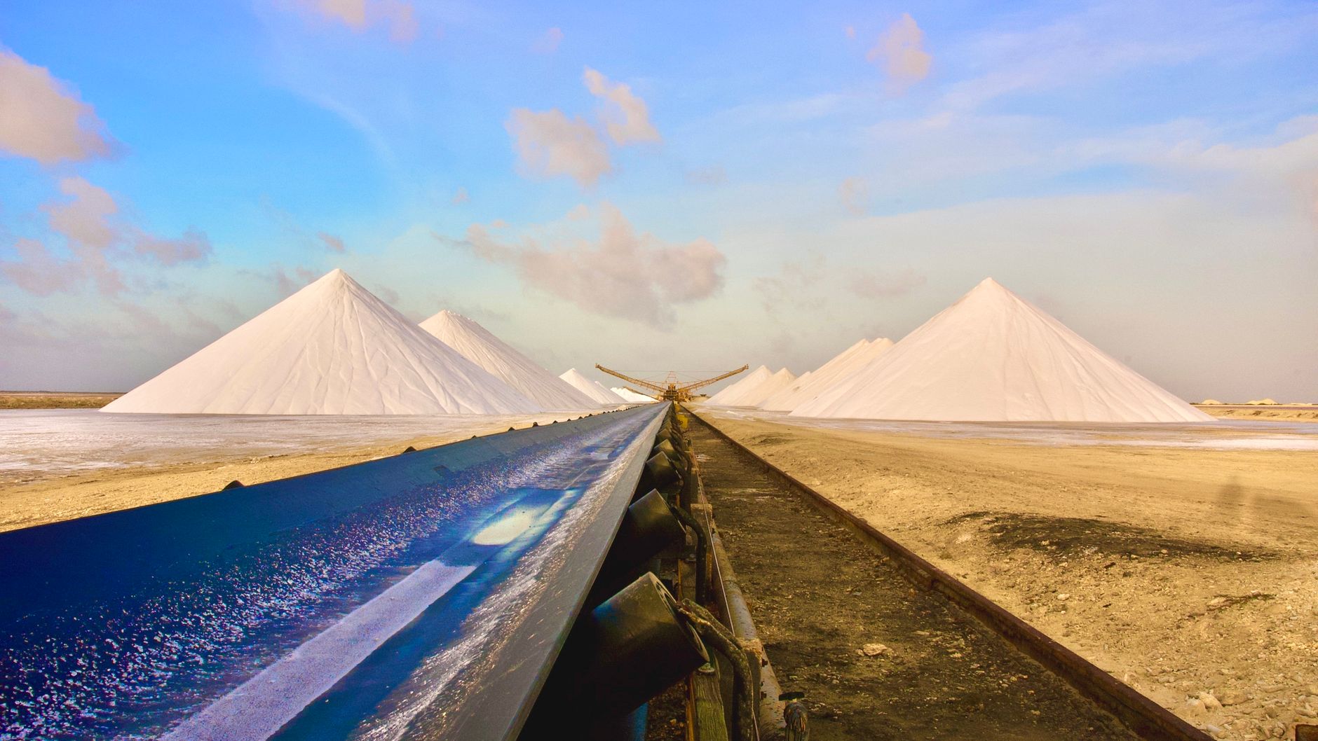 Industrial salt evaporation ponds and gleaming white crystallized salt pyramids under tropical sunlight in southern Bonaire