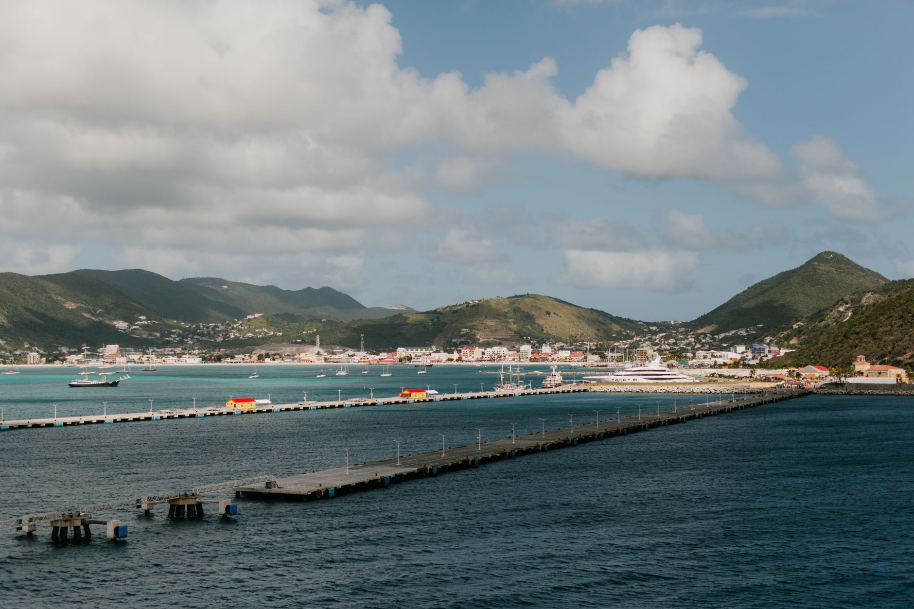 Waterfront boardwalk and harbor of Philipsburg in Sint Maarten backed by lush tropical mountain ridges