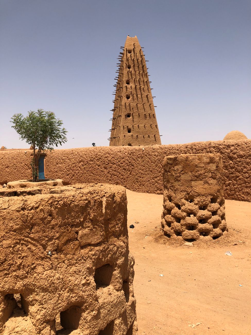 The twenty-seven meter earthen minaret of Agadez Grand Mosque rising above desert sand