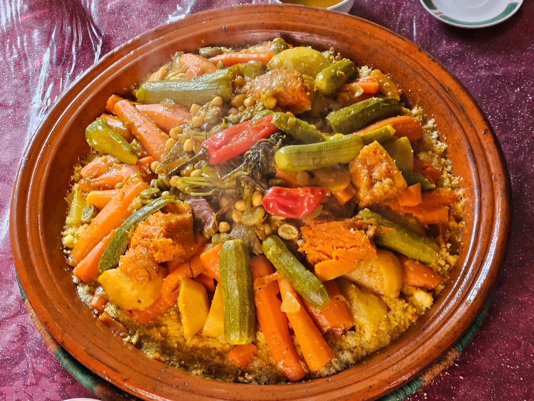 Steaming fine semolina couscous piled high with tender braised lamb, zucchini, carrots, and chickpeas in rich broth
