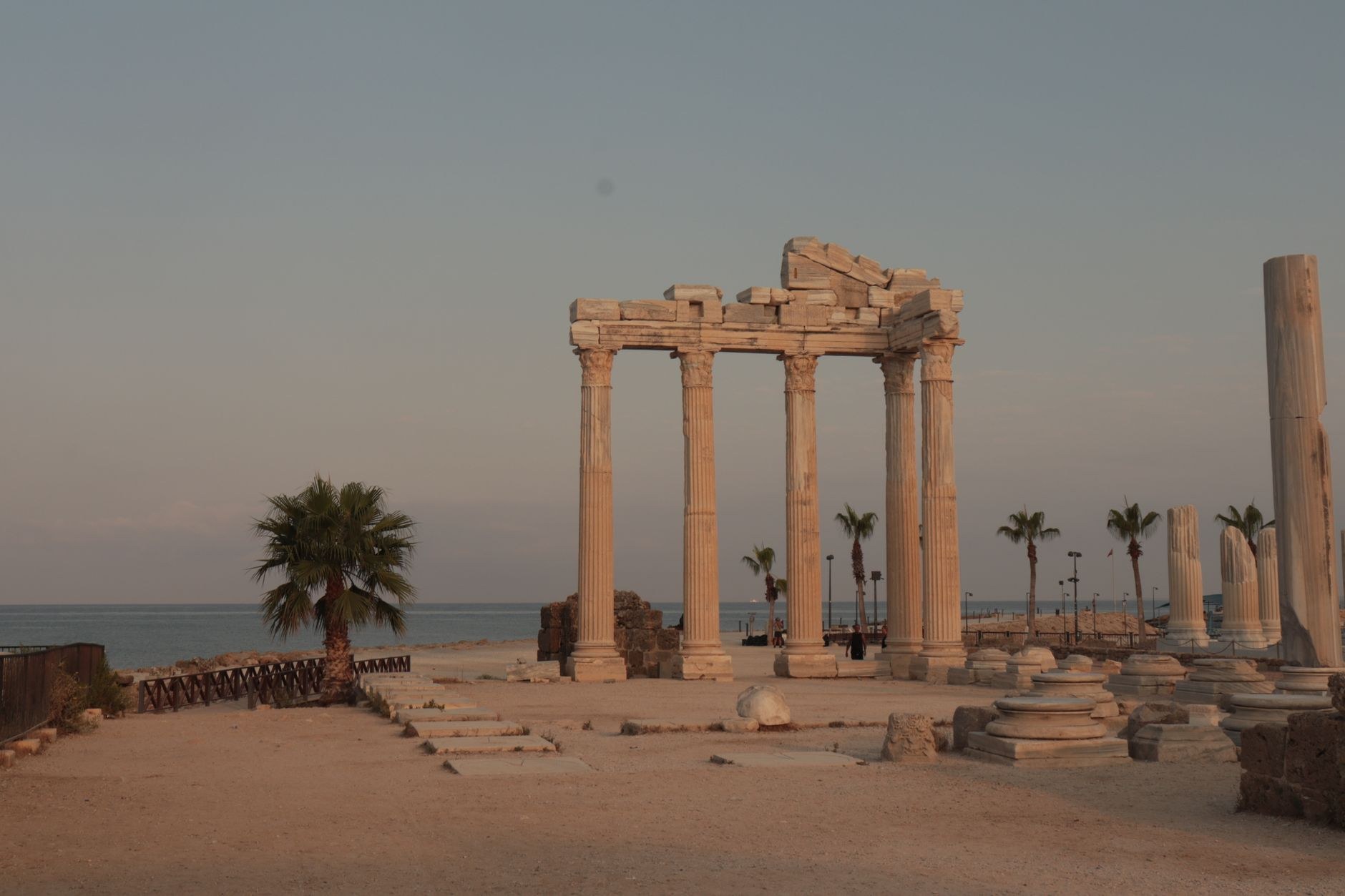 Ancient stone columns and Roman basilica ruins standing directly on pine-fringed cliffs above the blue Mediterranean Sea
