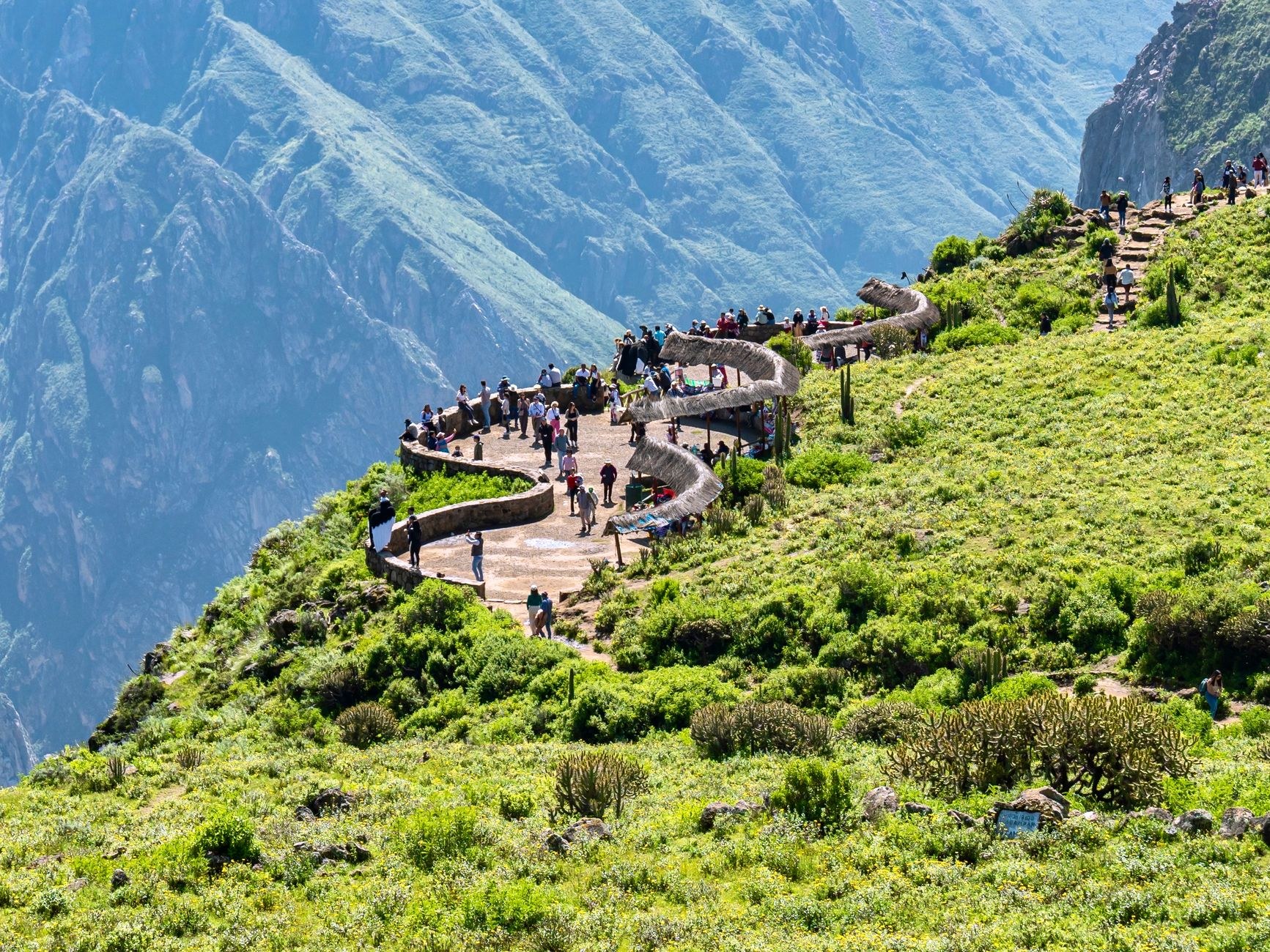 A long suspended glass-and-steel viewing platform extending out into space over a deep mountain valley