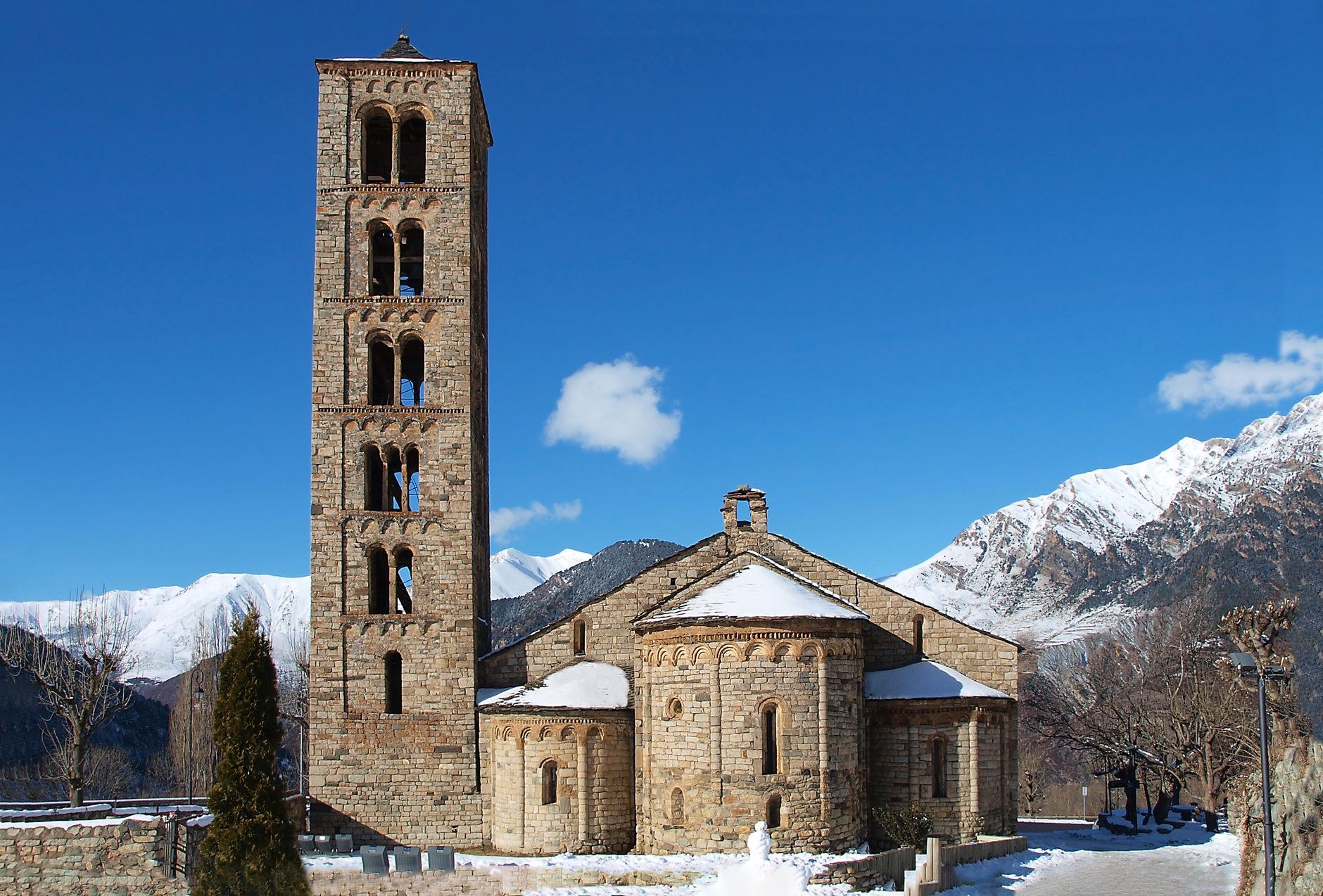 An 11th-century Romanesque stone church with a three-story rectangular bell tower and timber porch