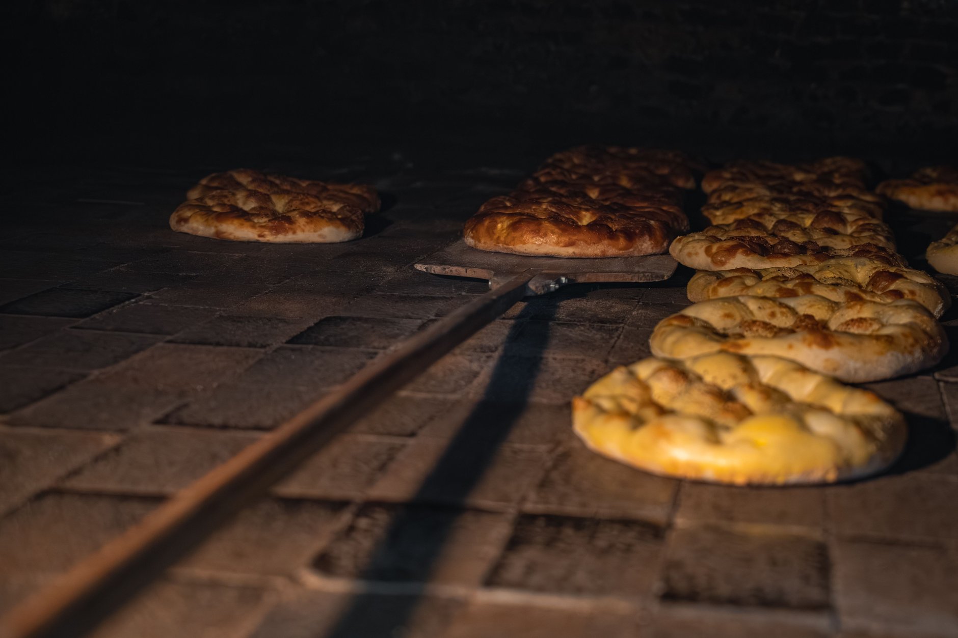 Traditional Armenian flatbread lavash being slapped onto the interior clay wall of an underground sunken tonir oven