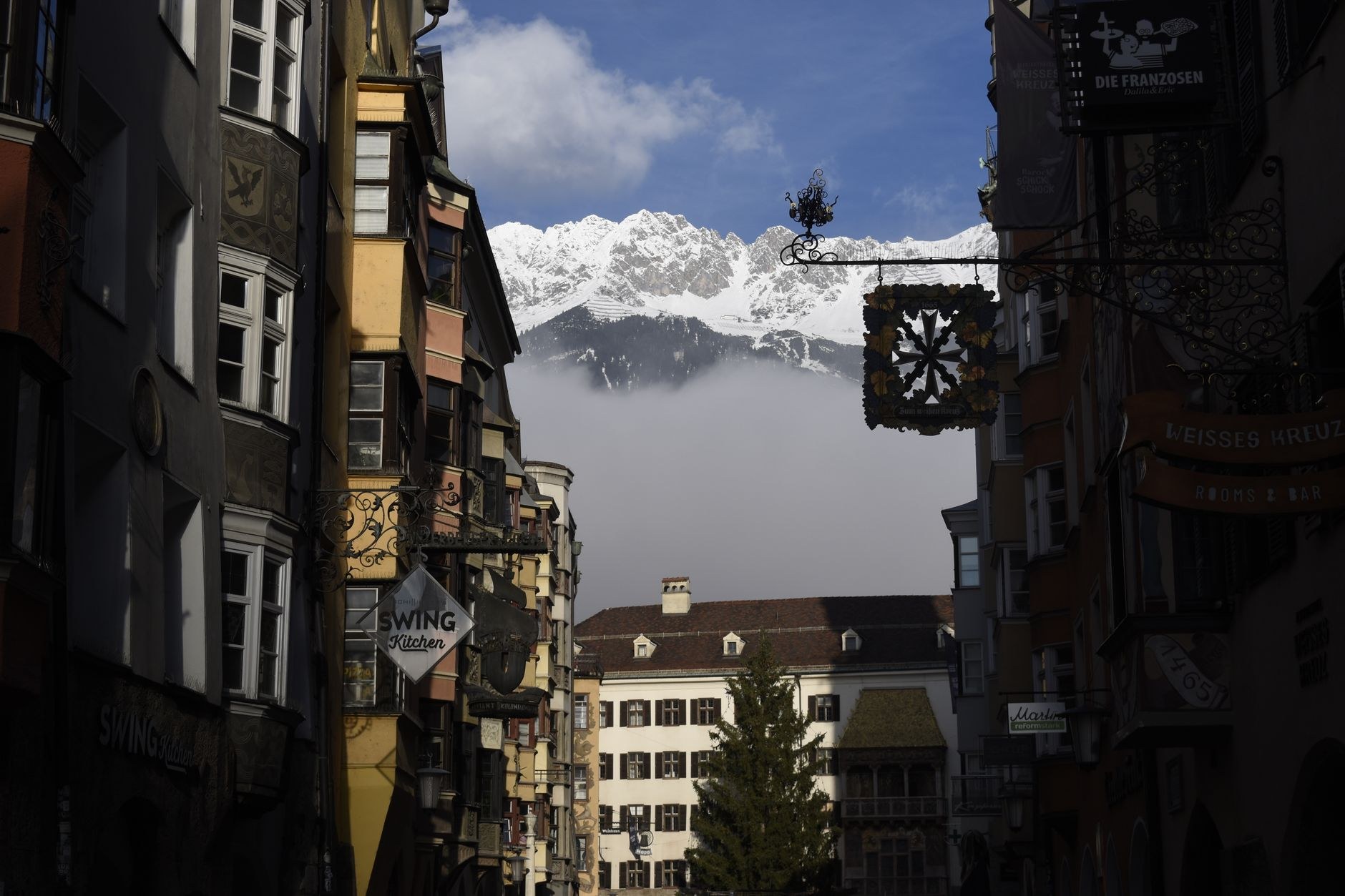 The colorful medieval buildings of Innsbruck's historic old town stand framed beneath the towering limestone peaks of the Nordkette range