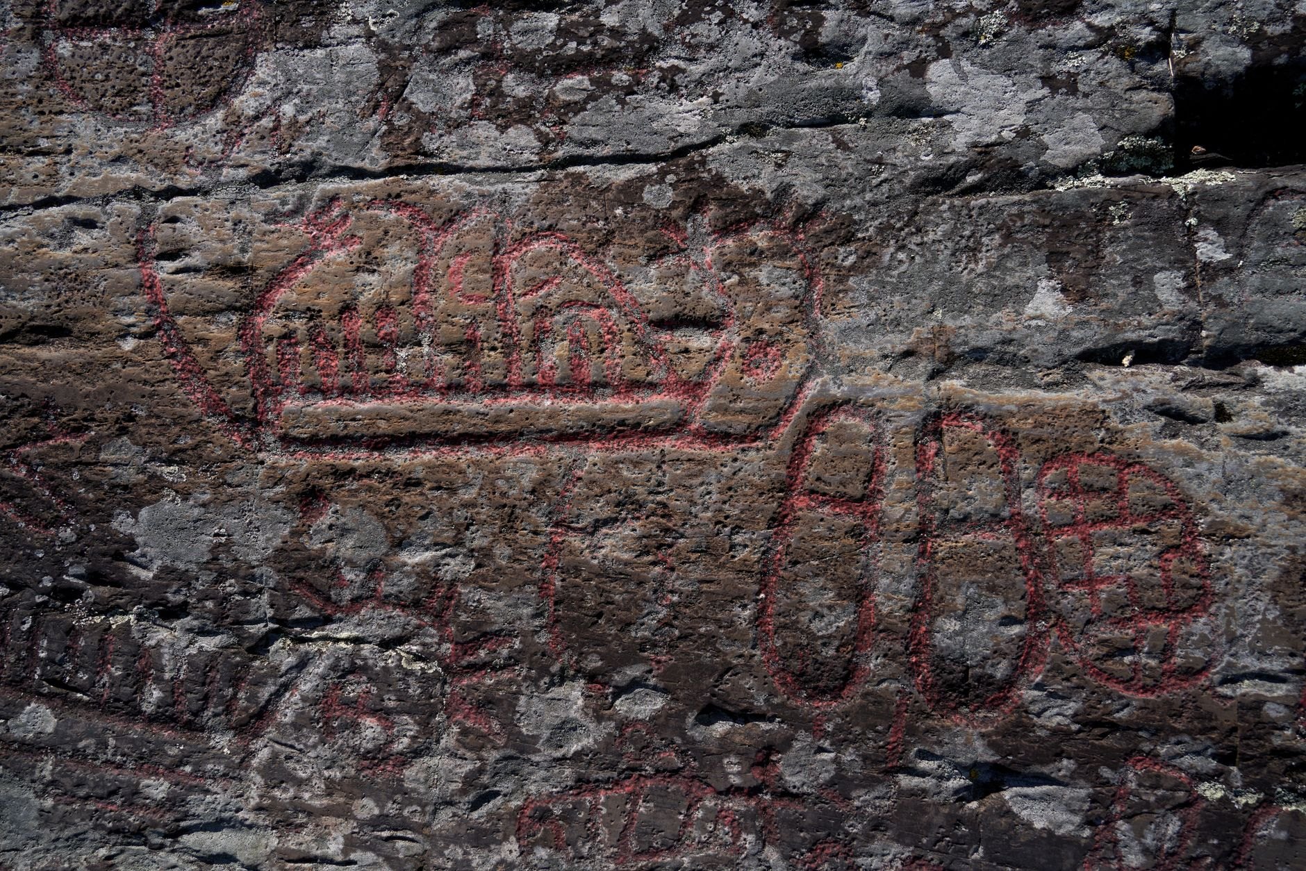 Prehistoric rock engravings depicting hunting figures and reed boats carved into limestone boulders in Gobustan