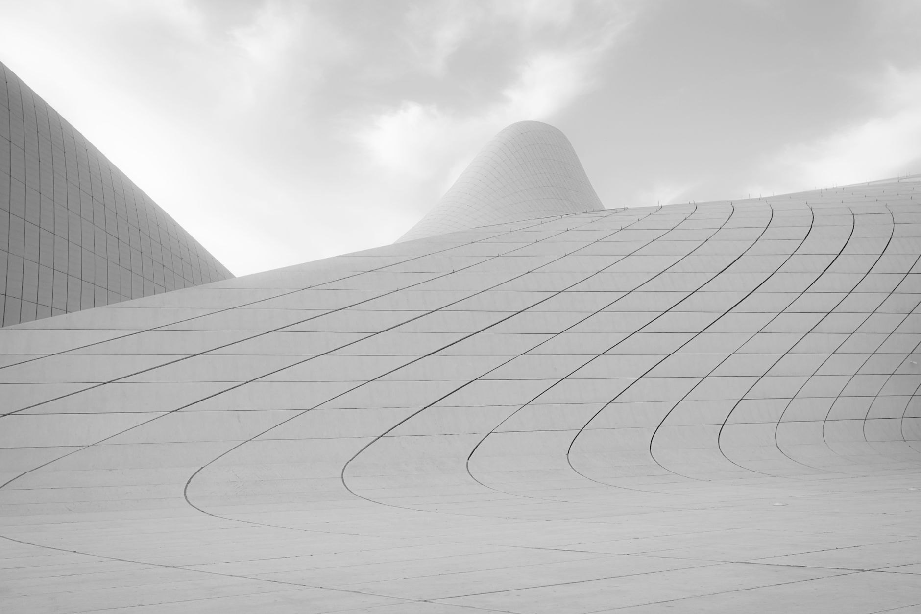 Flowing white futuristic curves of the Heydar Aliyev Center designed by architect Zaha Hadid under bright blue skies