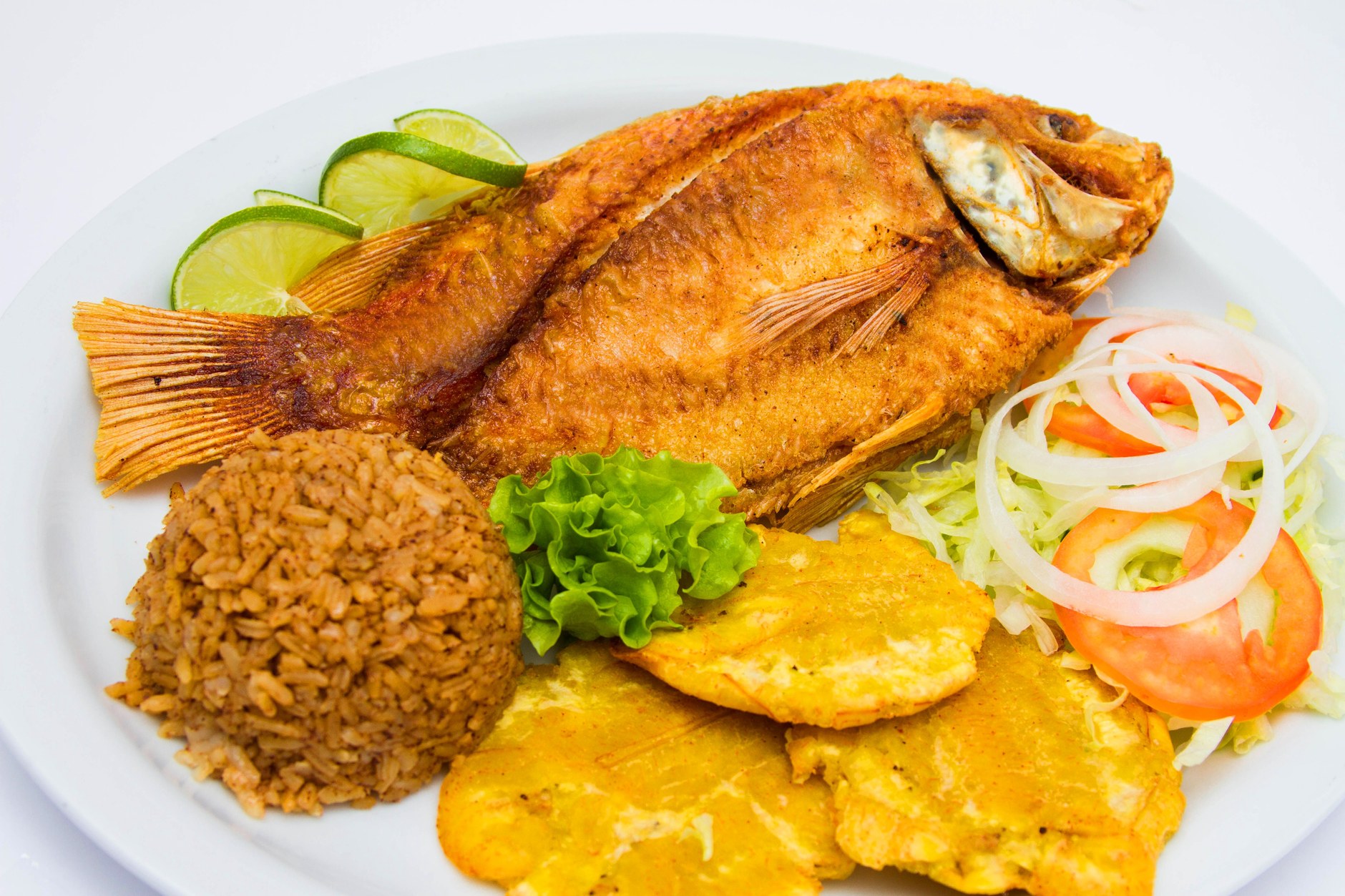 Plate of golden fried fish served with seasoned rice, plantains, and traditional Caribbean sides