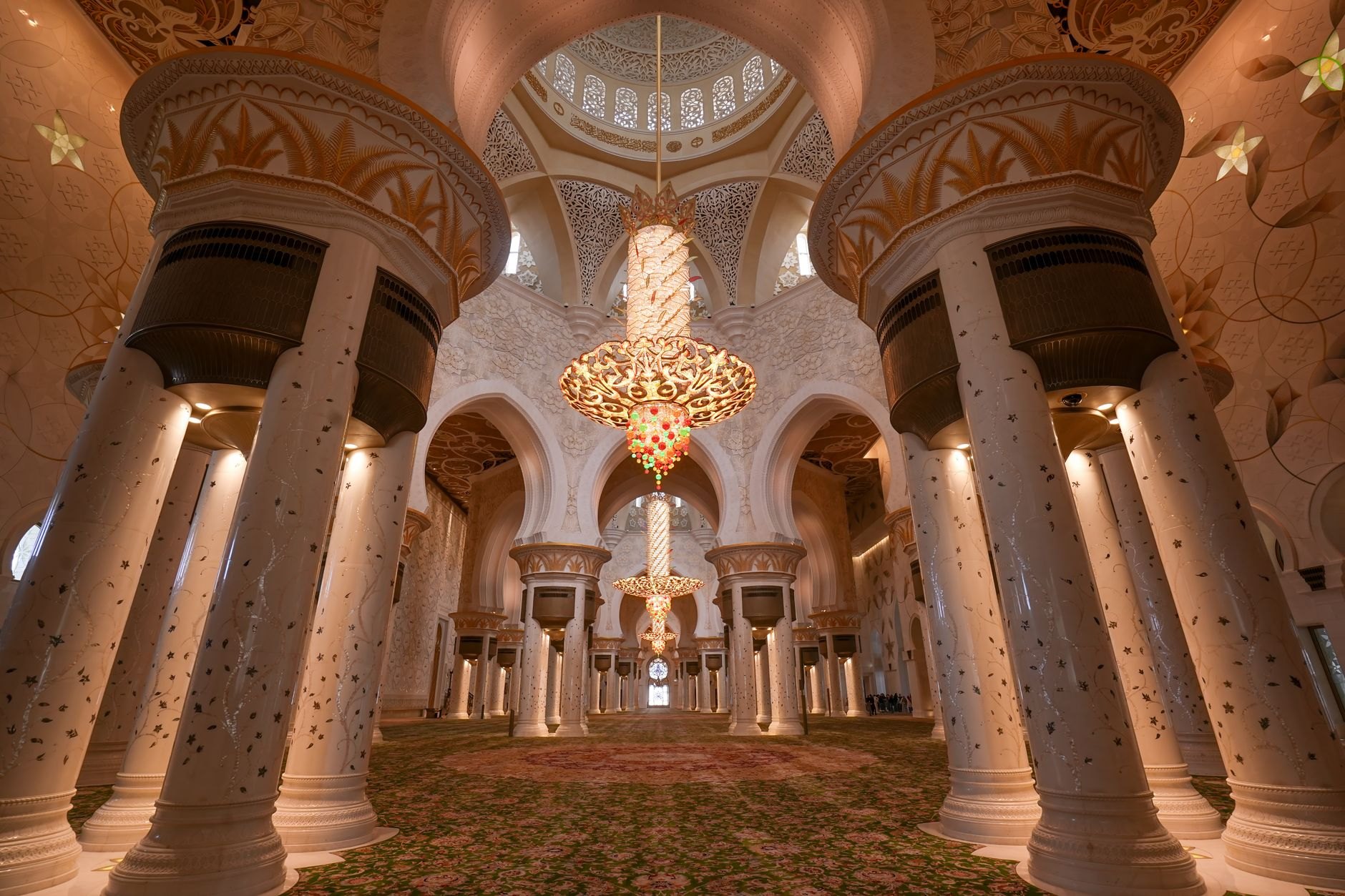 Vast marble prayer hall of Al Fateh Grand Mosque illuminated by huge brass chandeliers and stained-glass windows
