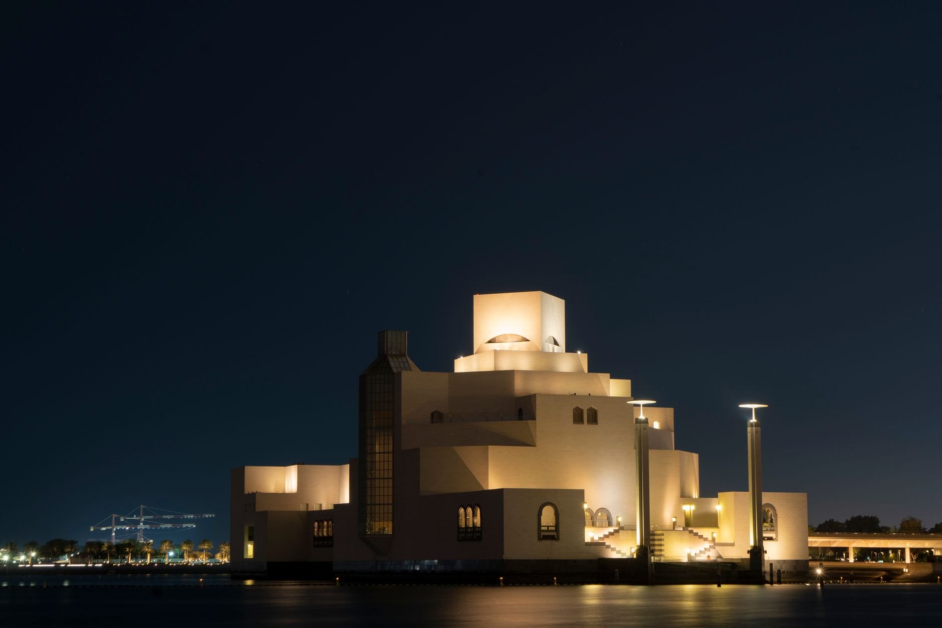 Sleek travertine stone pavilions and courtyards of the Bahrain National Museum bordering calm sea waters