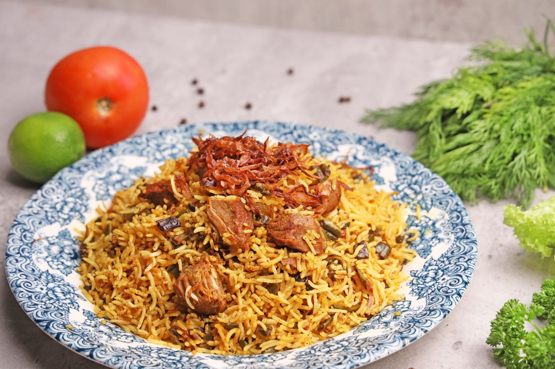 Fragrant platter of Dhaka kacchi biryani with spiced mutton, potatoes, boiled eggs, and mustard-marinated hilsa fish steak