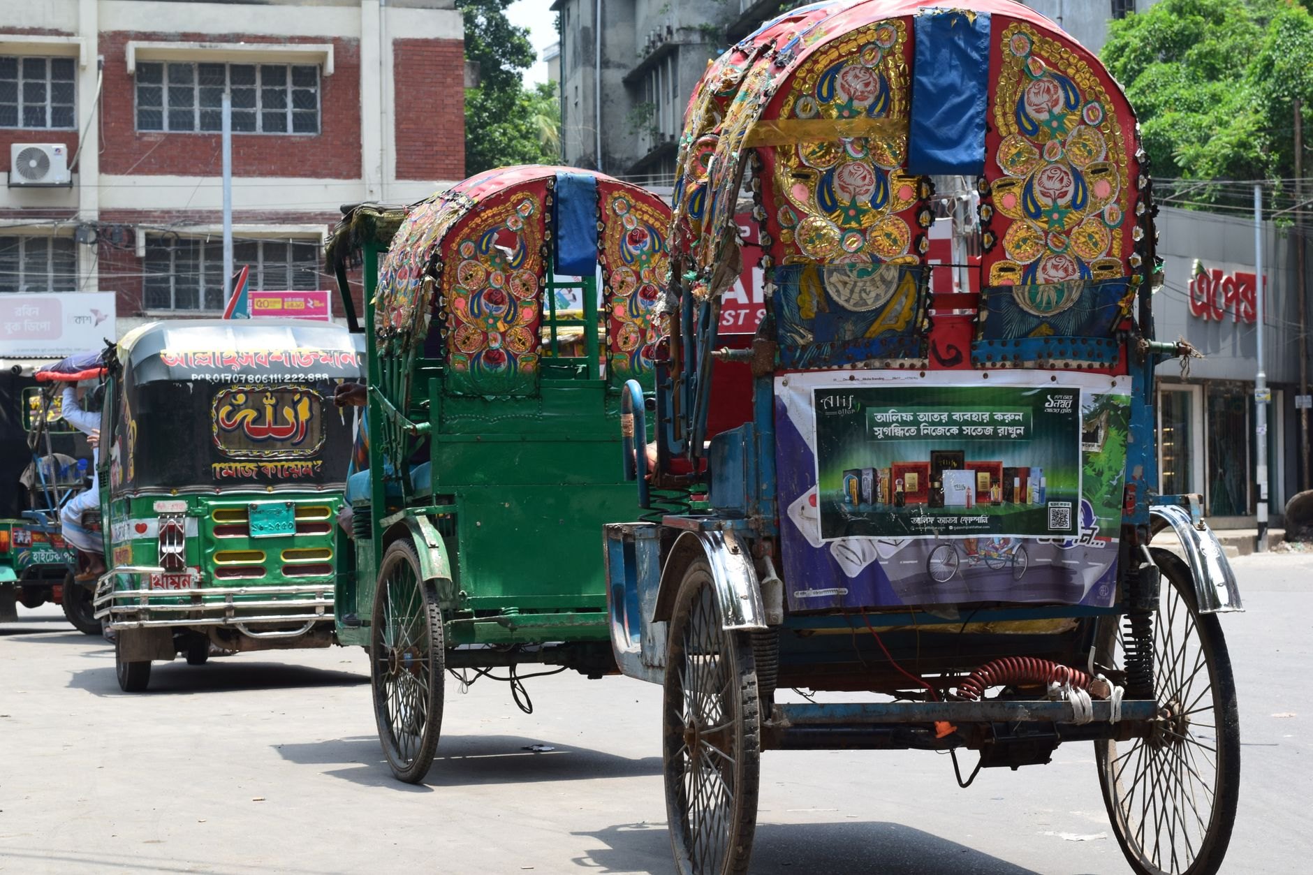 Intricately hand-painted cycle rickshaws with colorful floral tins and passenger hoods crowding a bustling street in Old Dhaka